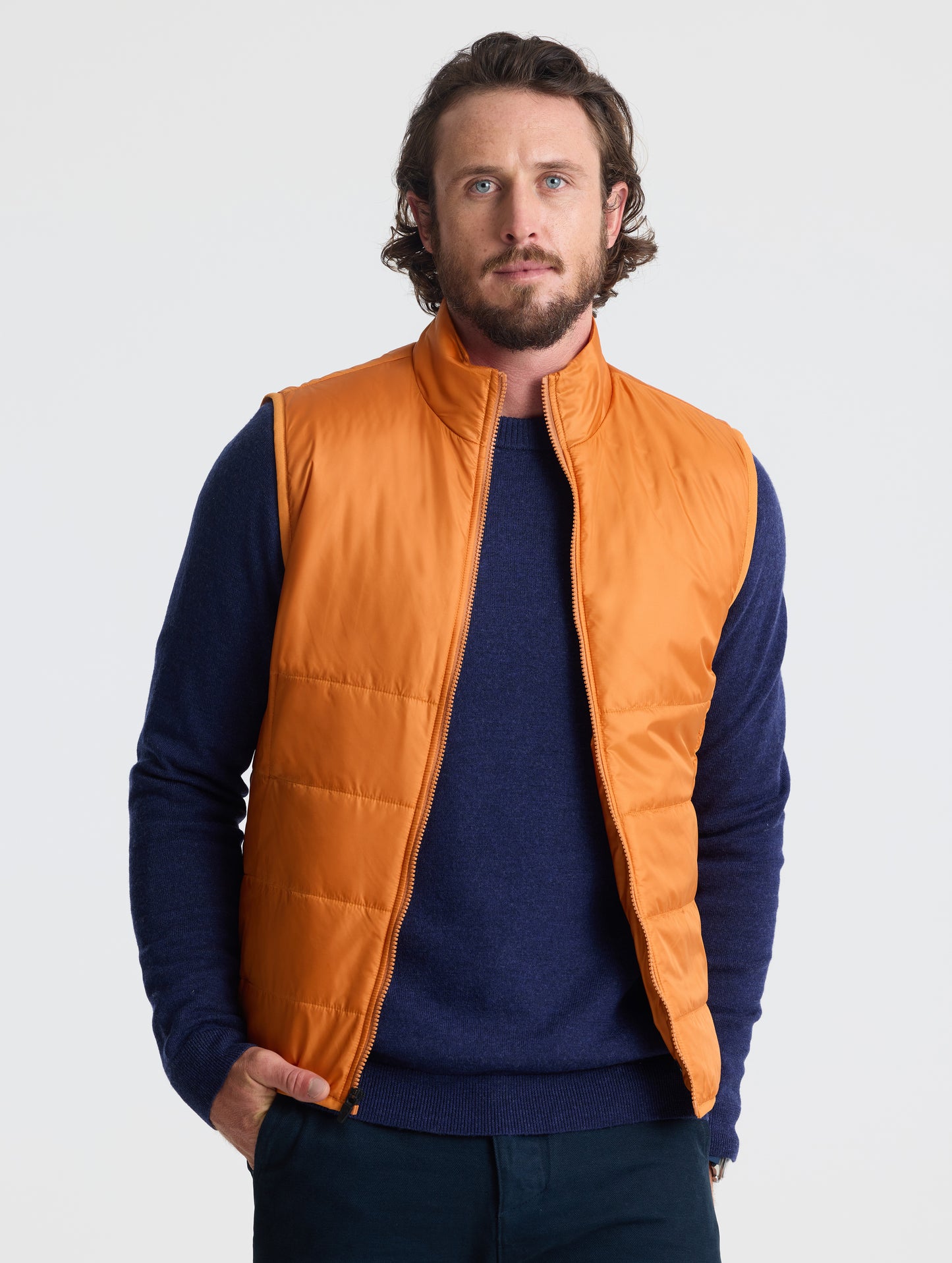 Front view of man wearing unzipped Eco Insulated Vest in Autumn Orange from AETHER Apparel.