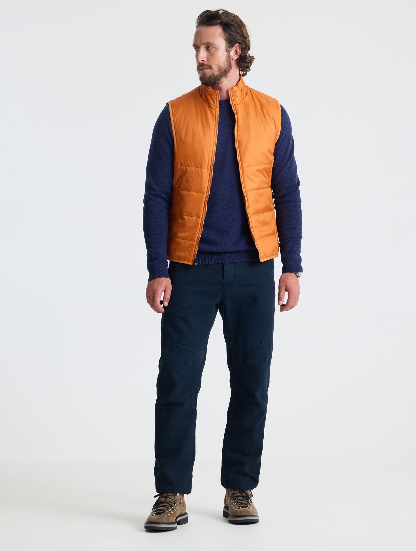 Full body view of man wearing Eco Insulated Vest in Autumn Orange from AETHER Apparel.