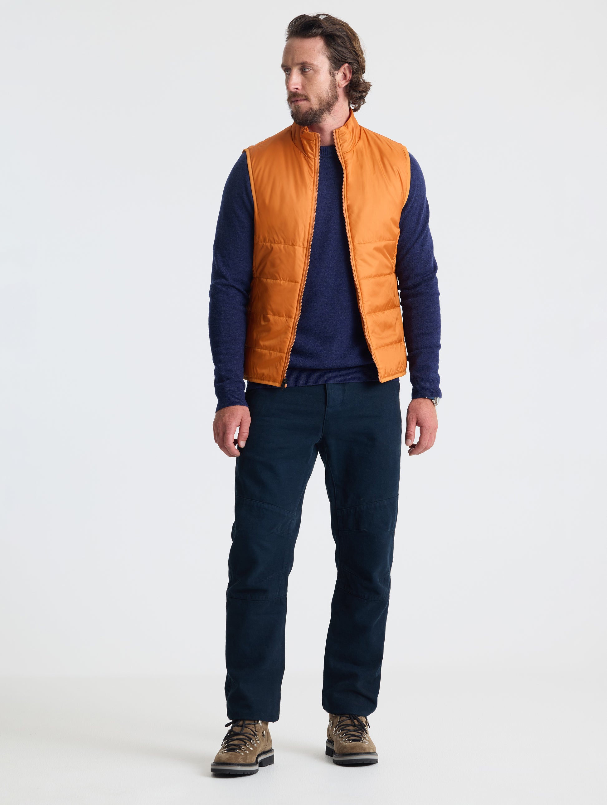 Full body view of man wearing Eco Insulated Vest in Autumn Orange from AETHER Apparel.