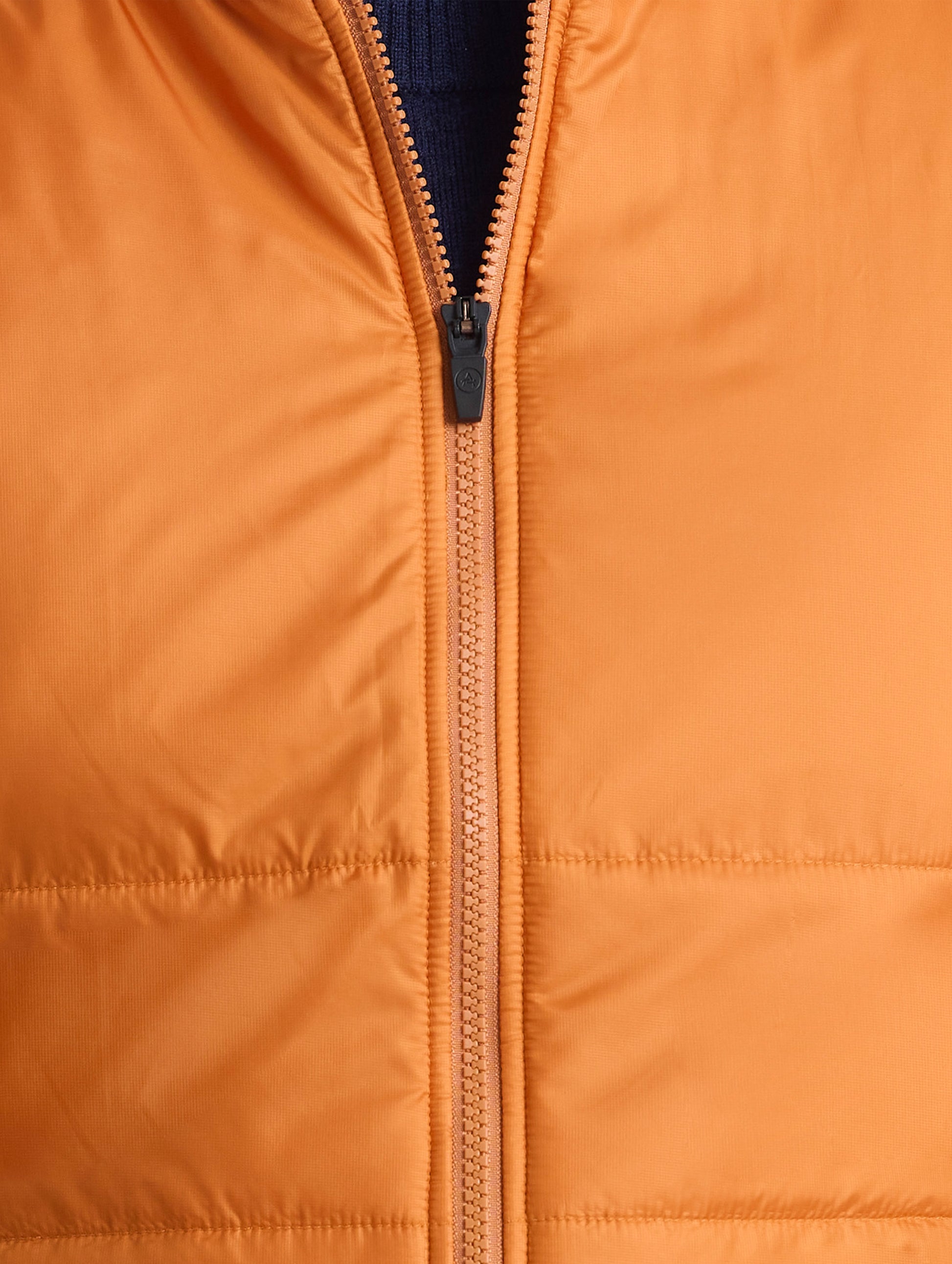 Closeup view of front center zipper of Eco Insulated Vest in Autumn Orange from AETHER Apparel.
