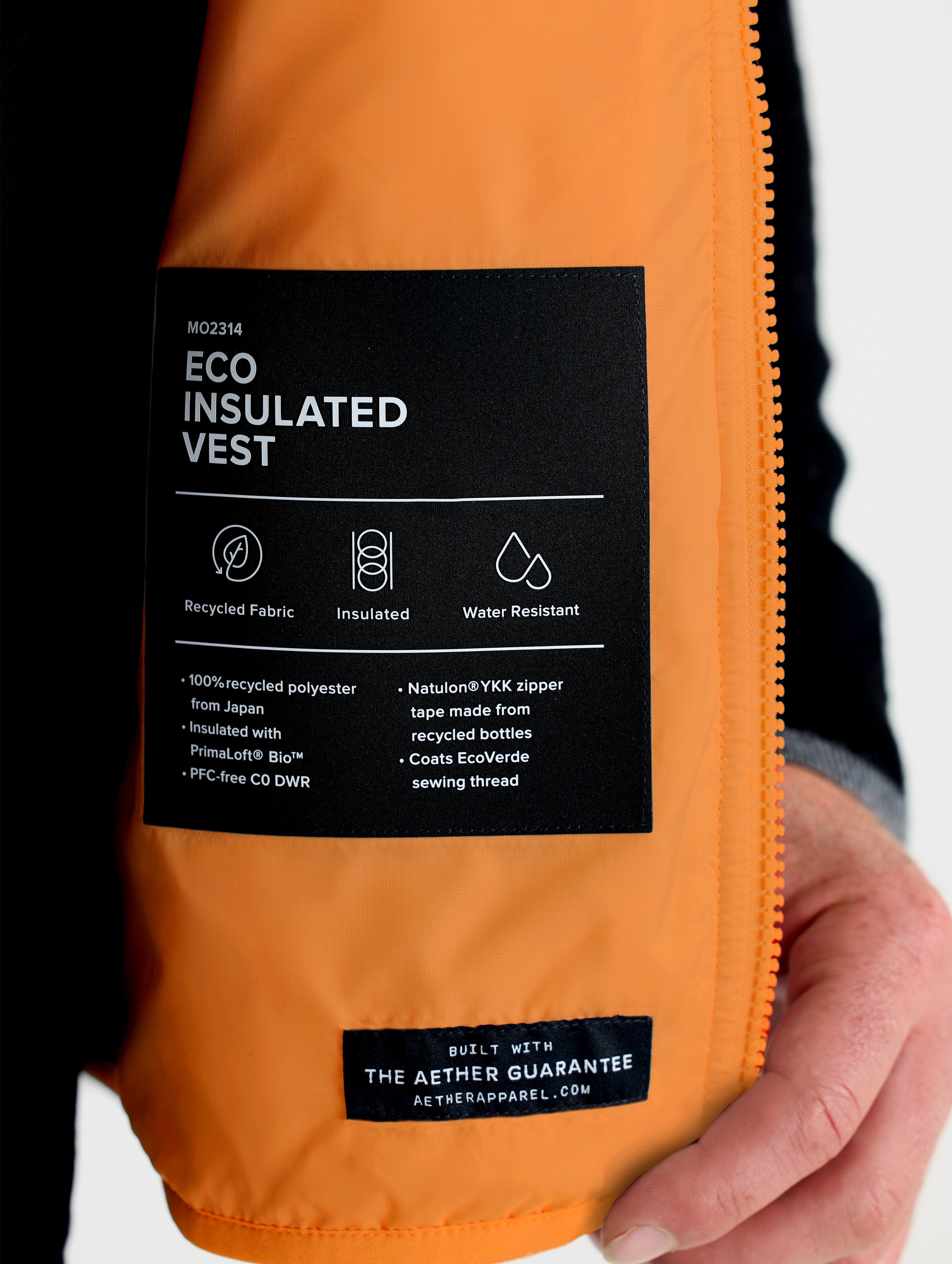 Closeup view of wearer's left interior pocket of Eco Insulated Vest in Autumn Orange from AETHER Apparel.
