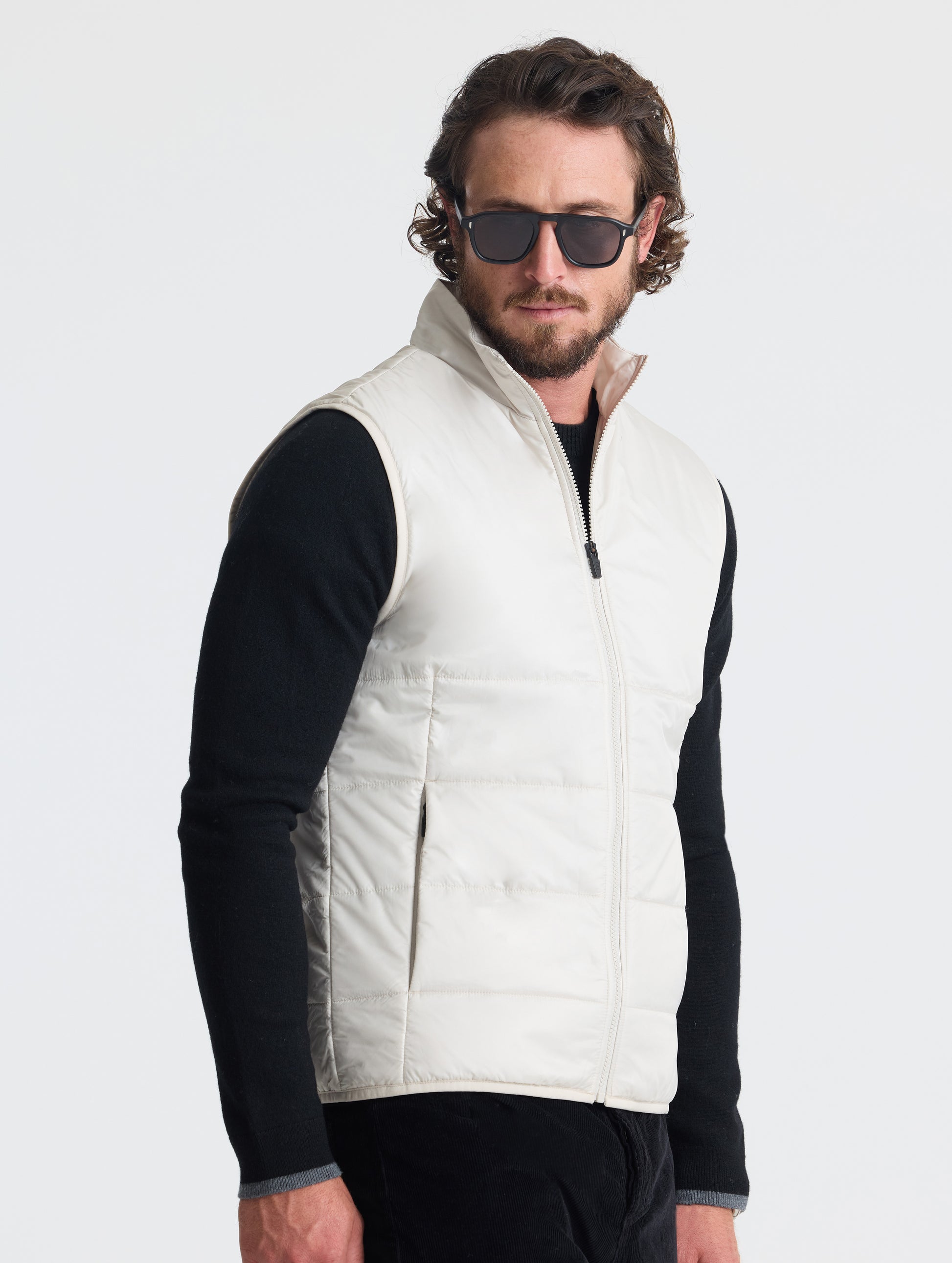 Angled view of man wearing Eco Insulated Vest in Bone white from AETHER Apparel.