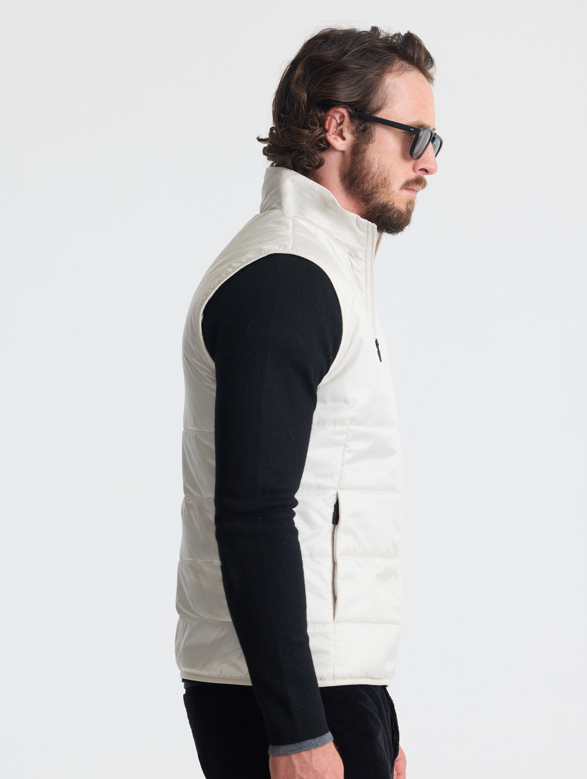 Right profile view of man wearing Eco Insulated Vest in Bone white from AETHER Apparel.
