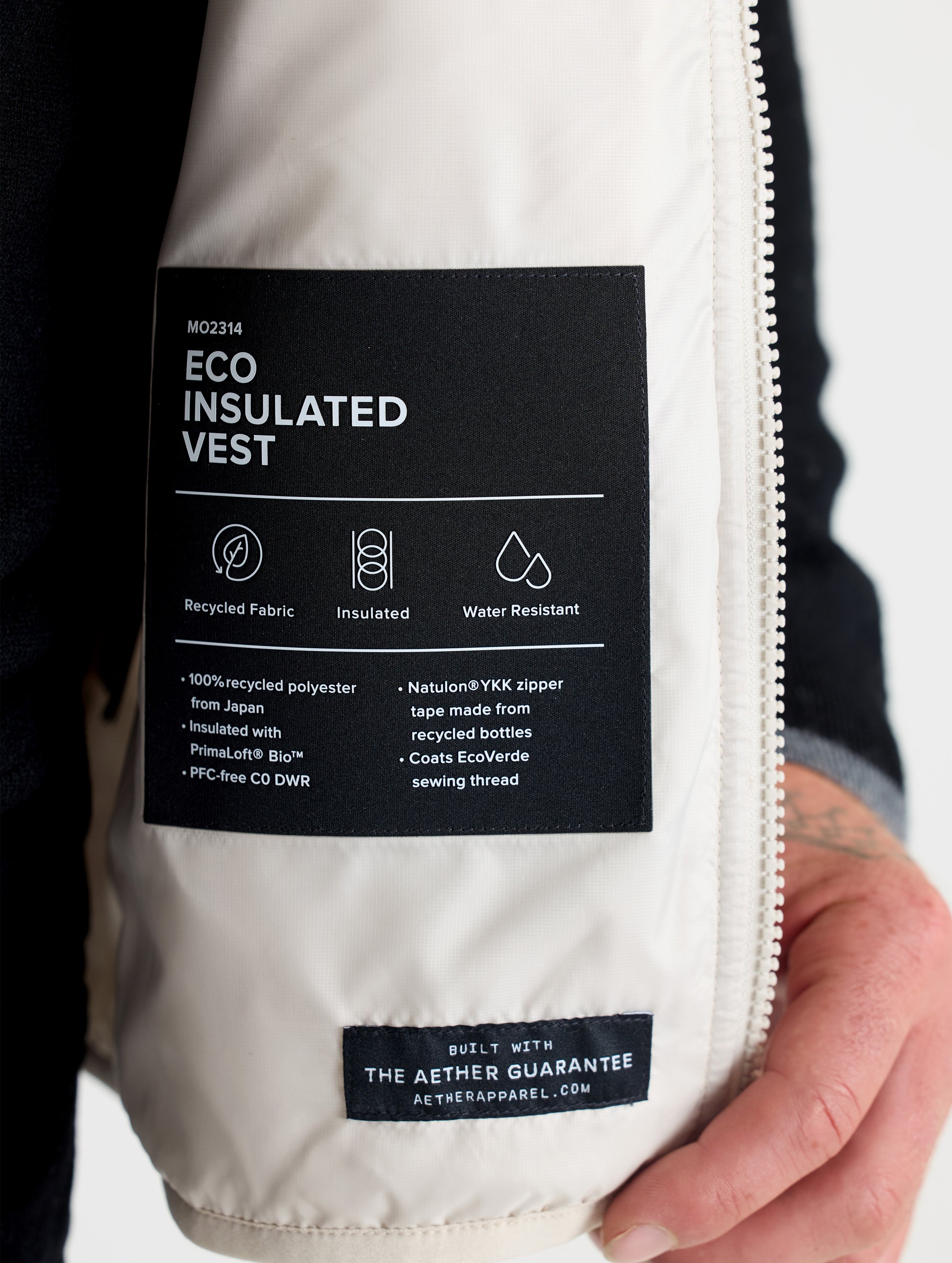 Closeup view of wearer's interior left label of Eco Insulated Vest in Bone white from AETHER Apparel.