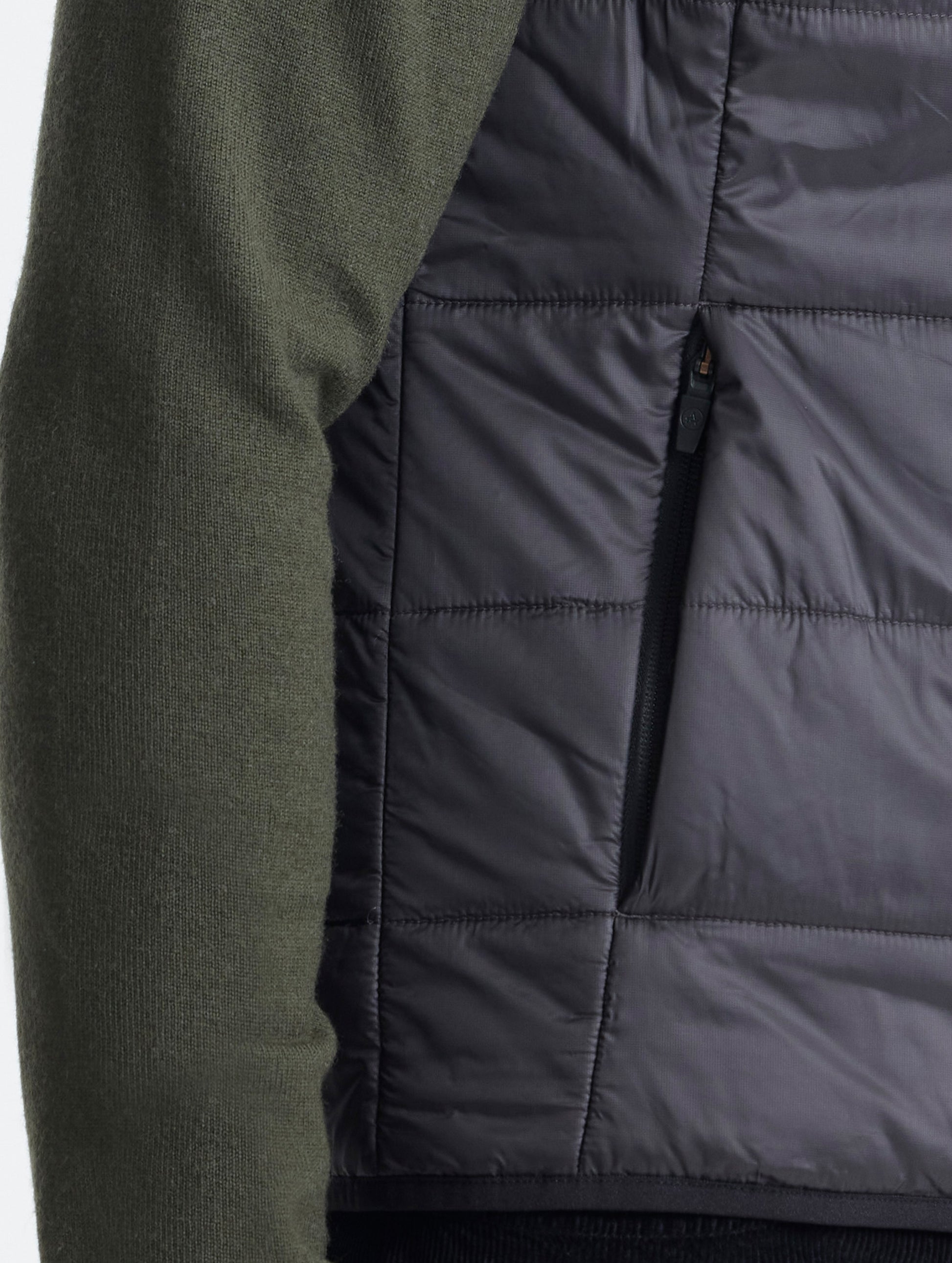 Closeup view of wearer's right hand pocket of Eco Insulated Vest in Onyx Black from AETHER Apparel.