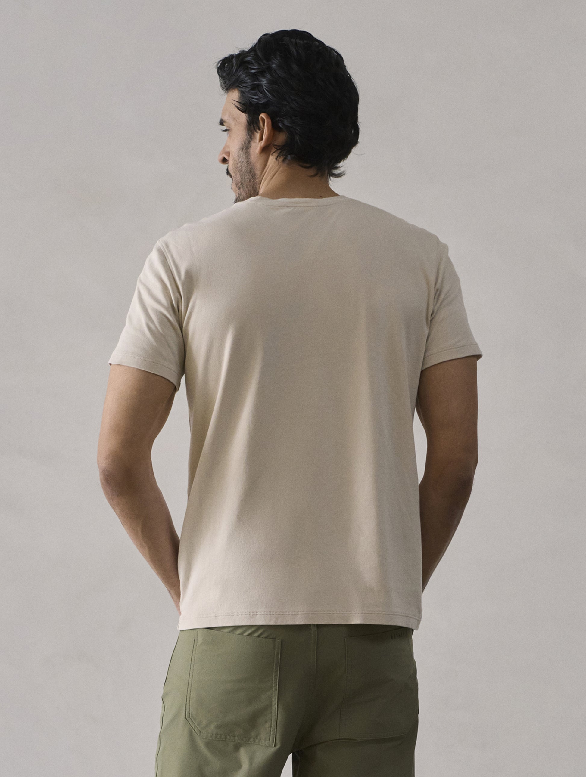 Rear view of man wearing Emery Pima Crew Tee in Bone white from AETHER Apparel.