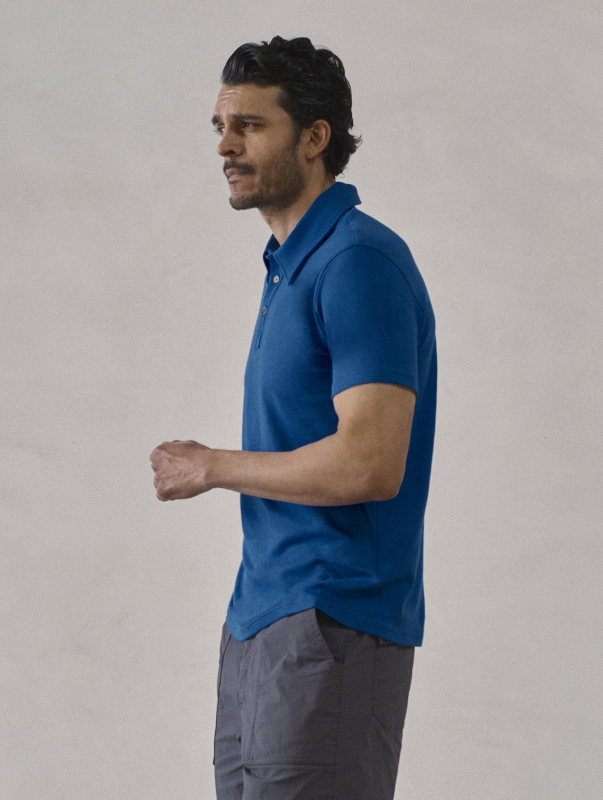Side profile view of man wearing Emery Pima Polo in Summit Blue from AETHER Apparel.