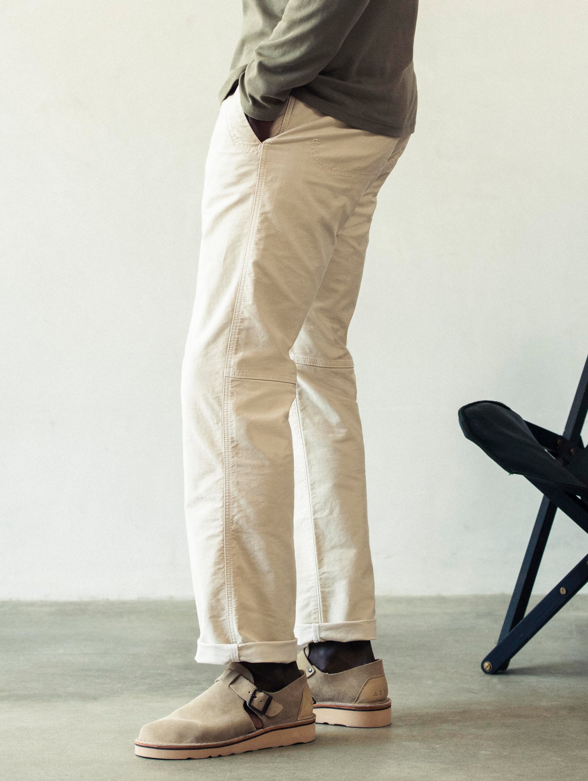 Left side profile lower body view of man wearing Fairfax Pant 2.0 in Bone white from AETHER Apparel.