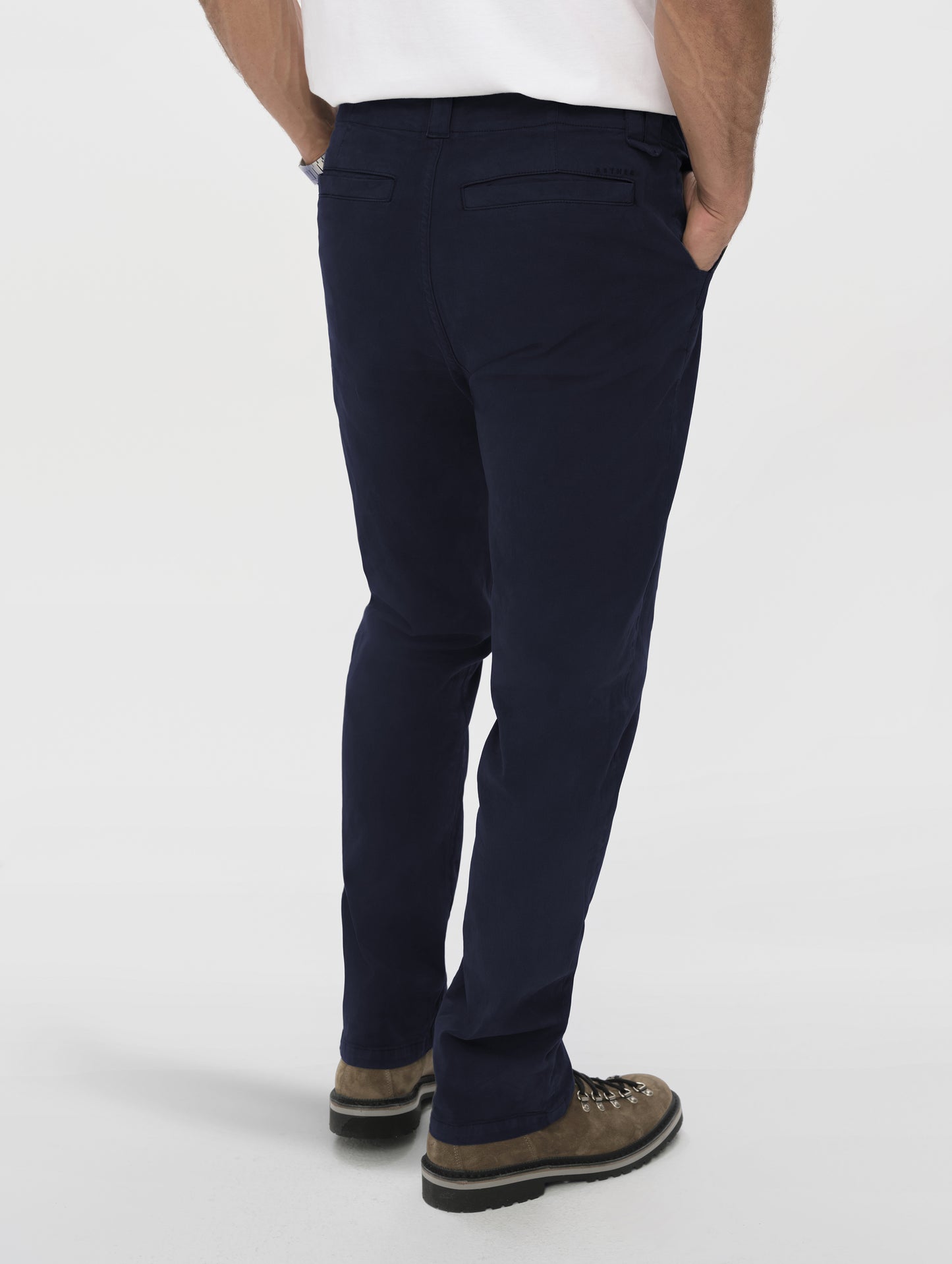 Rear angled lower-body view of man wearing the Flint Chino Pant in Total Eclipse dark blue from AETHER Apparel.