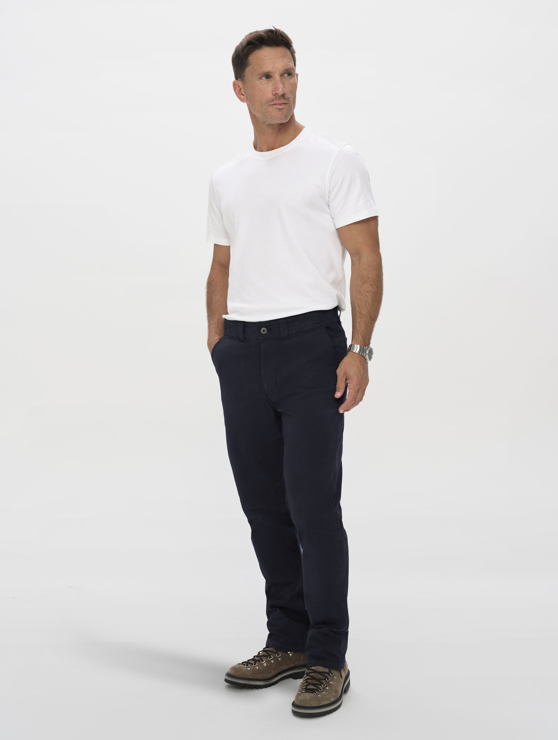 Front angled full-body view of man wearing the Flint Chino Pant in Total Eclipse dark blue from AETHER Apparel.