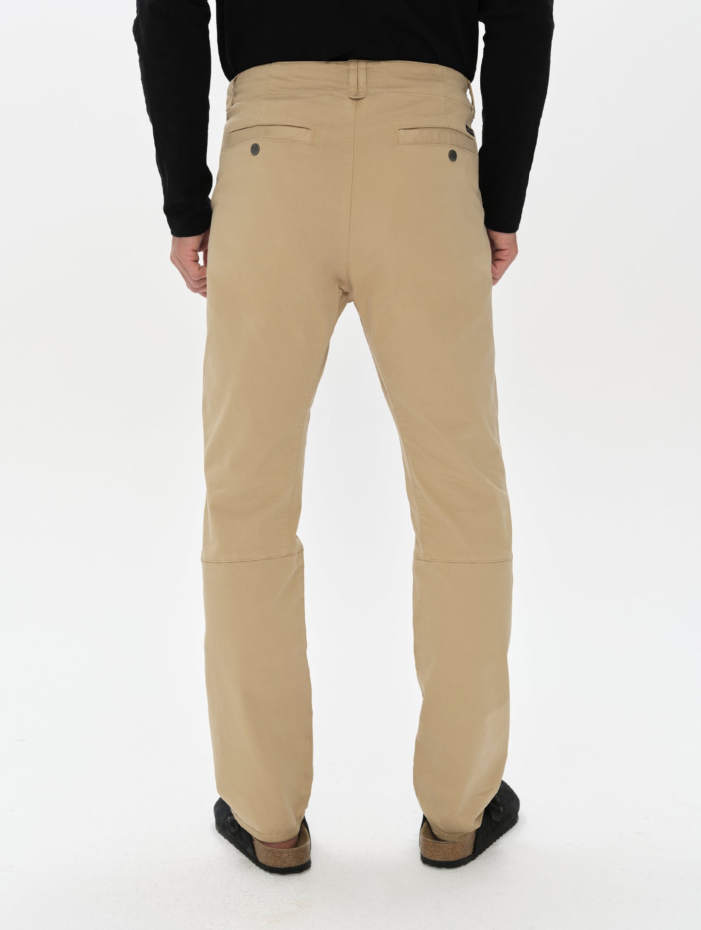 Rear, lower-body view of man wearing the Gabriel Articulated Chino in Desert Tan from AETHER Apparel.