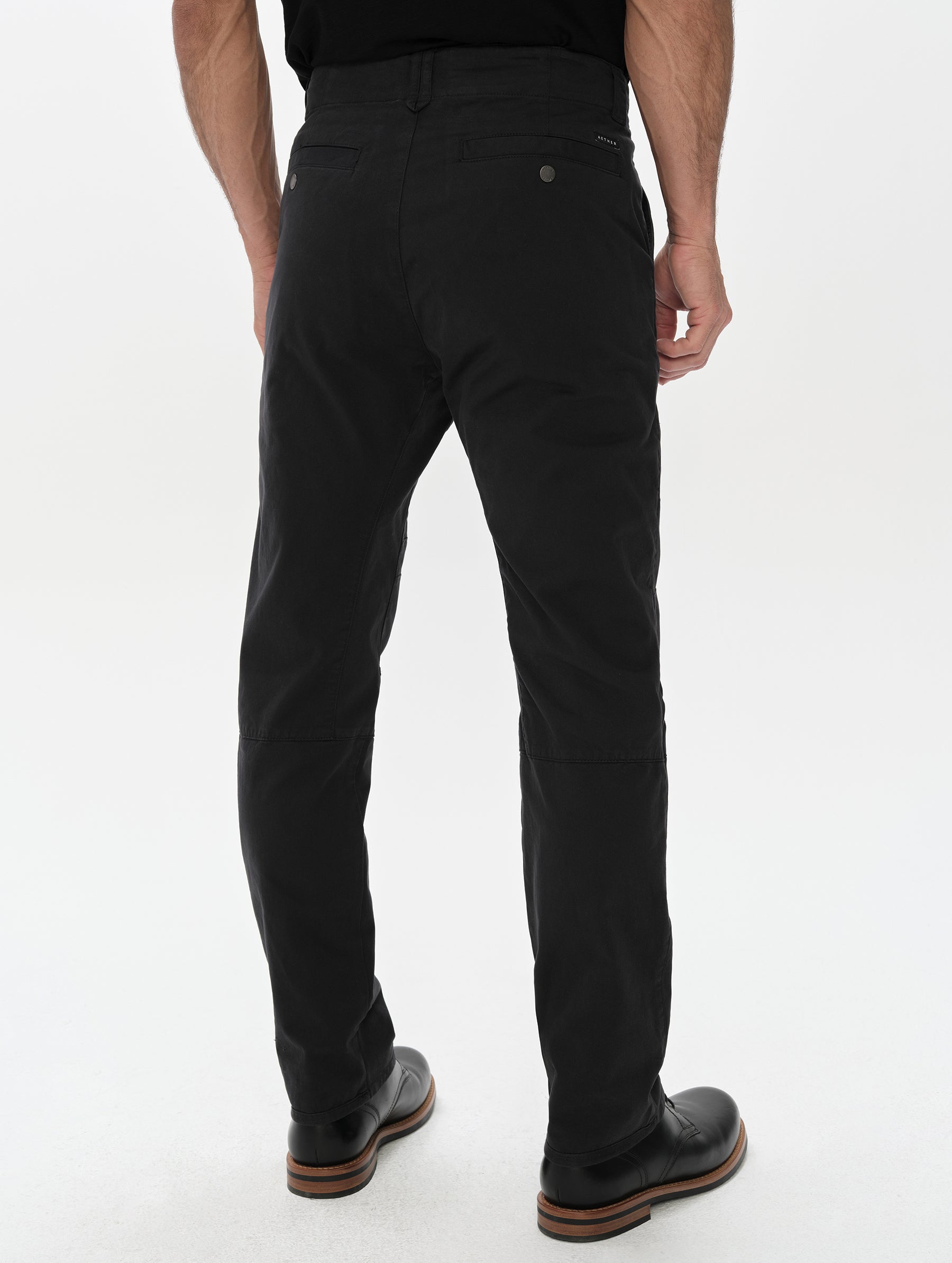 Rear, lower-body view of man wearing the Gabriel Articulated Chino in Onyx Black from AETHER Apparel.