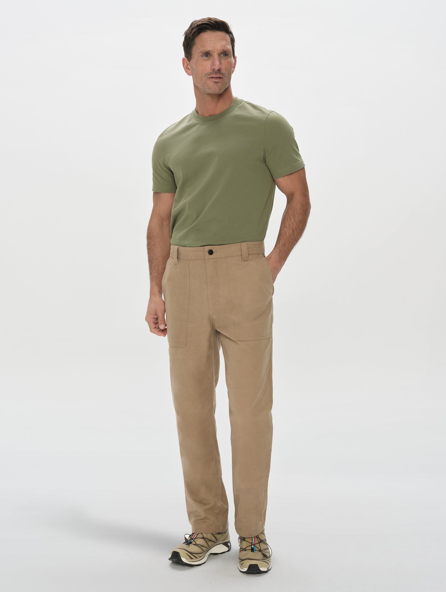 Front, full-body view of man wearing the Gage Cotton Pant in Desert Tan from AETHER Apparel.