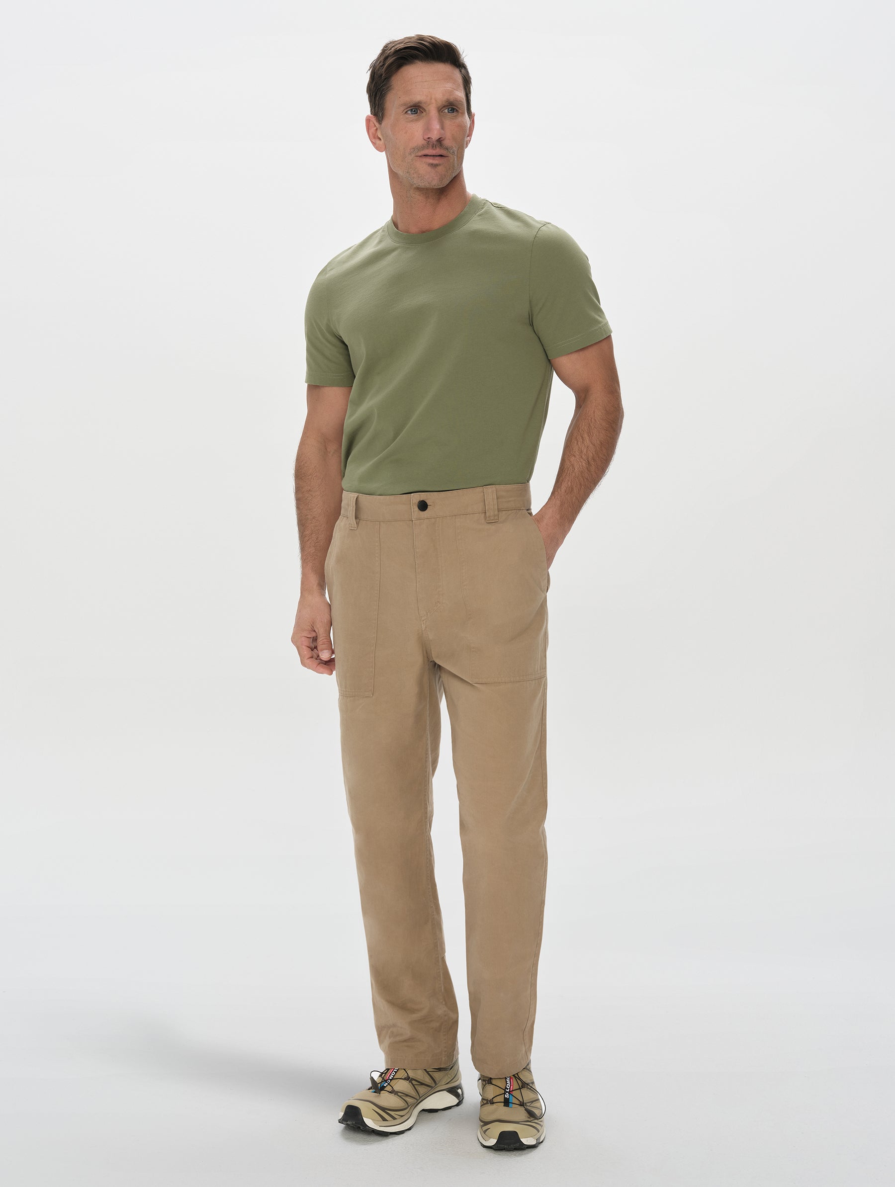 Front, full-body view of man wearing the Gage Cotton Pant in Desert Tan from AETHER Apparel.