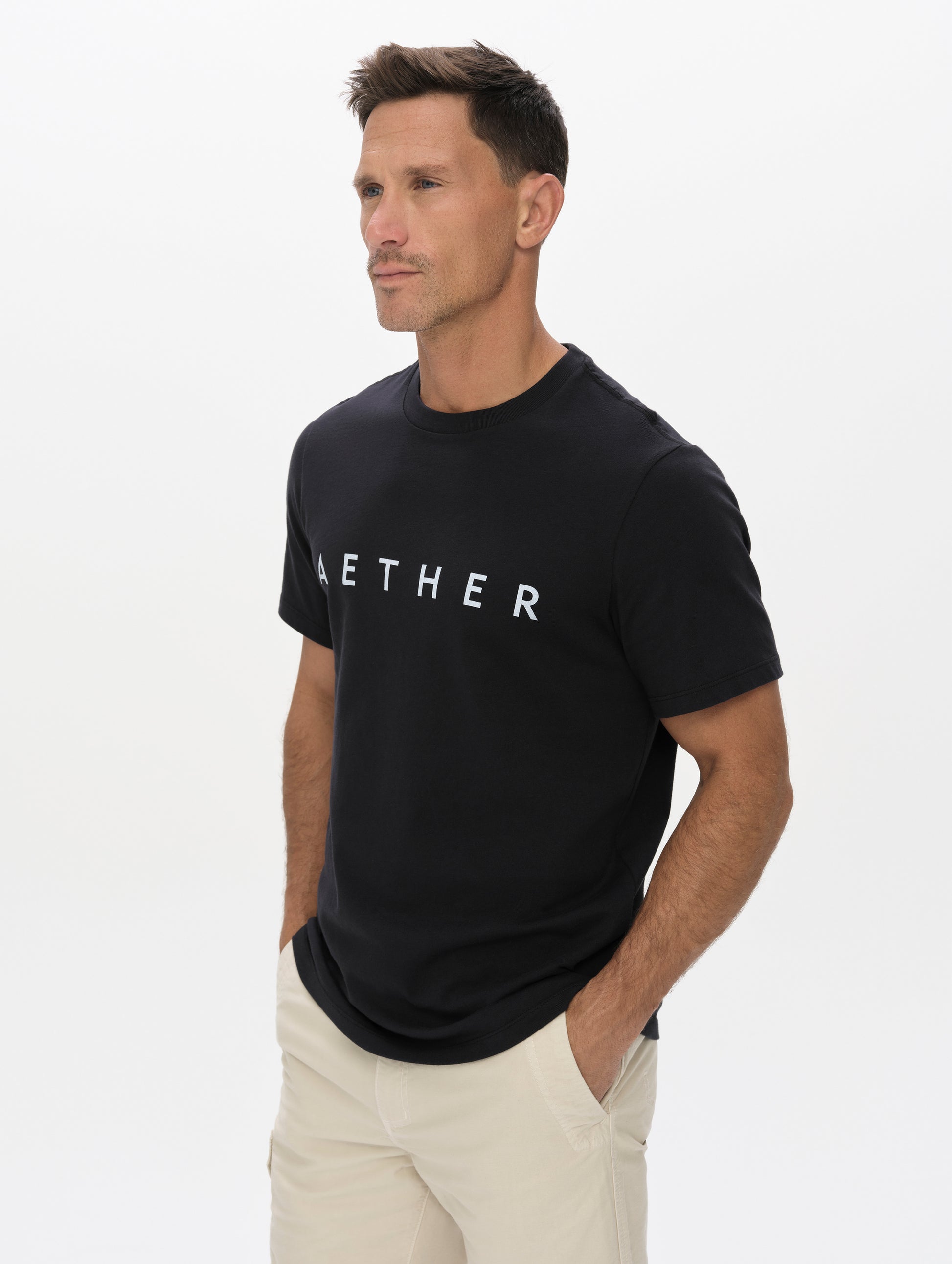 Front, angled upper-body view of man wearing the Graphic Tee AETHER Logo in Onyx Black from AETHER Apparel.