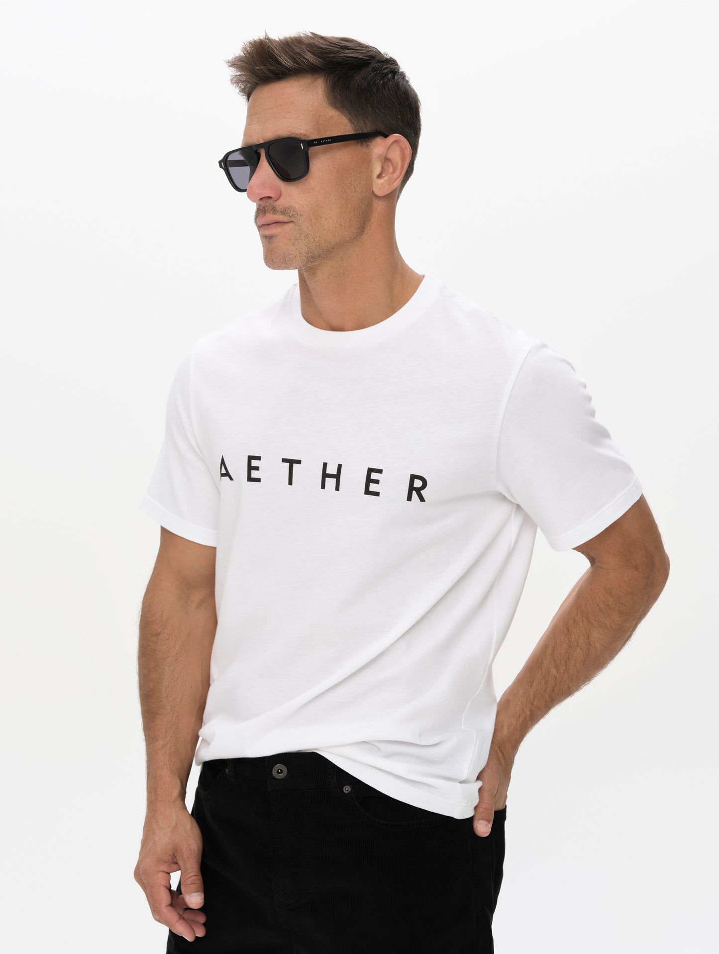 Front, angled upper-body view of man wearing the Graphic Tee AETHER Logo in White from AETHER Apparel.