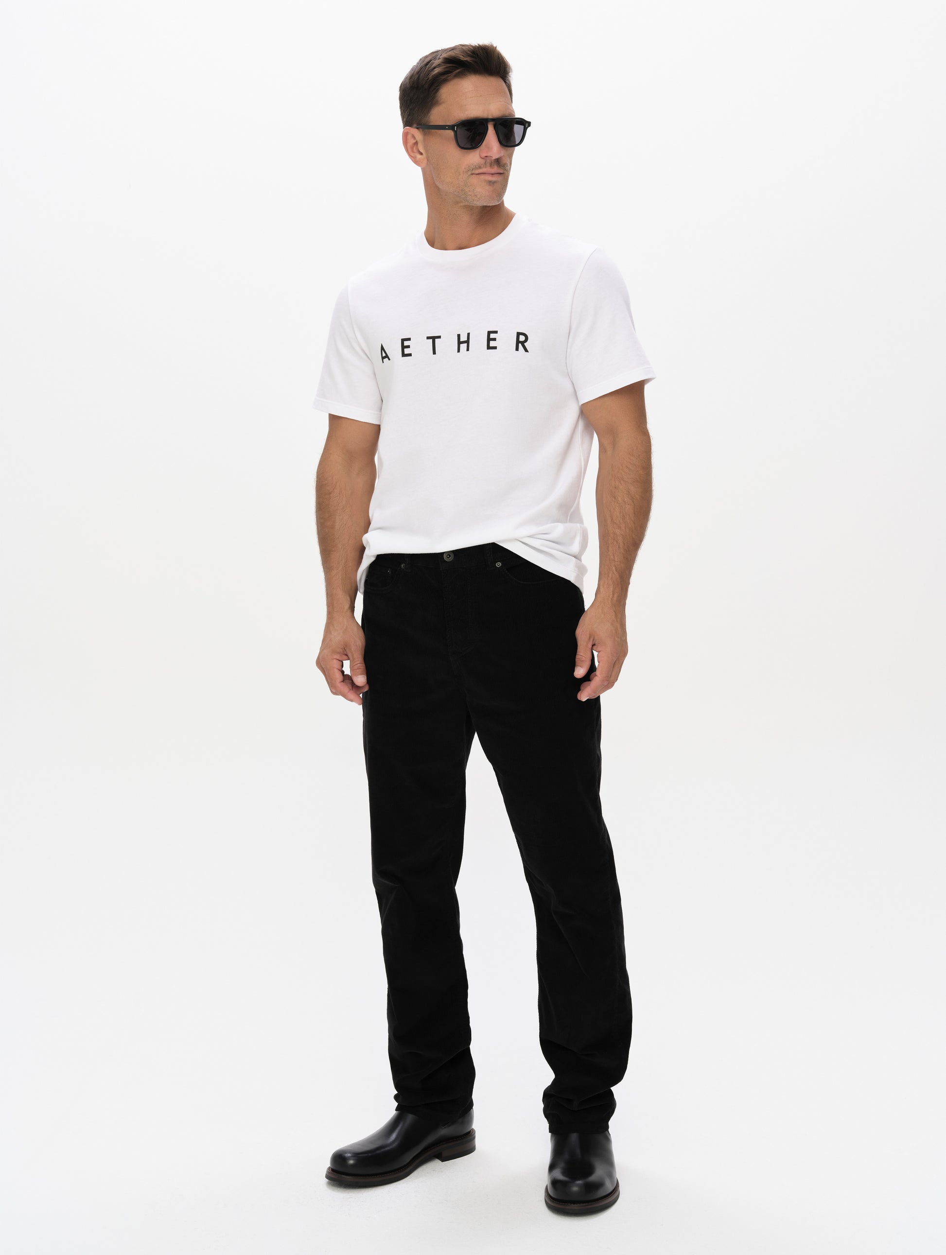 Front, angled full-body view of man wearing the Graphic Tee AETHER Logo in White from AETHER Apparel.