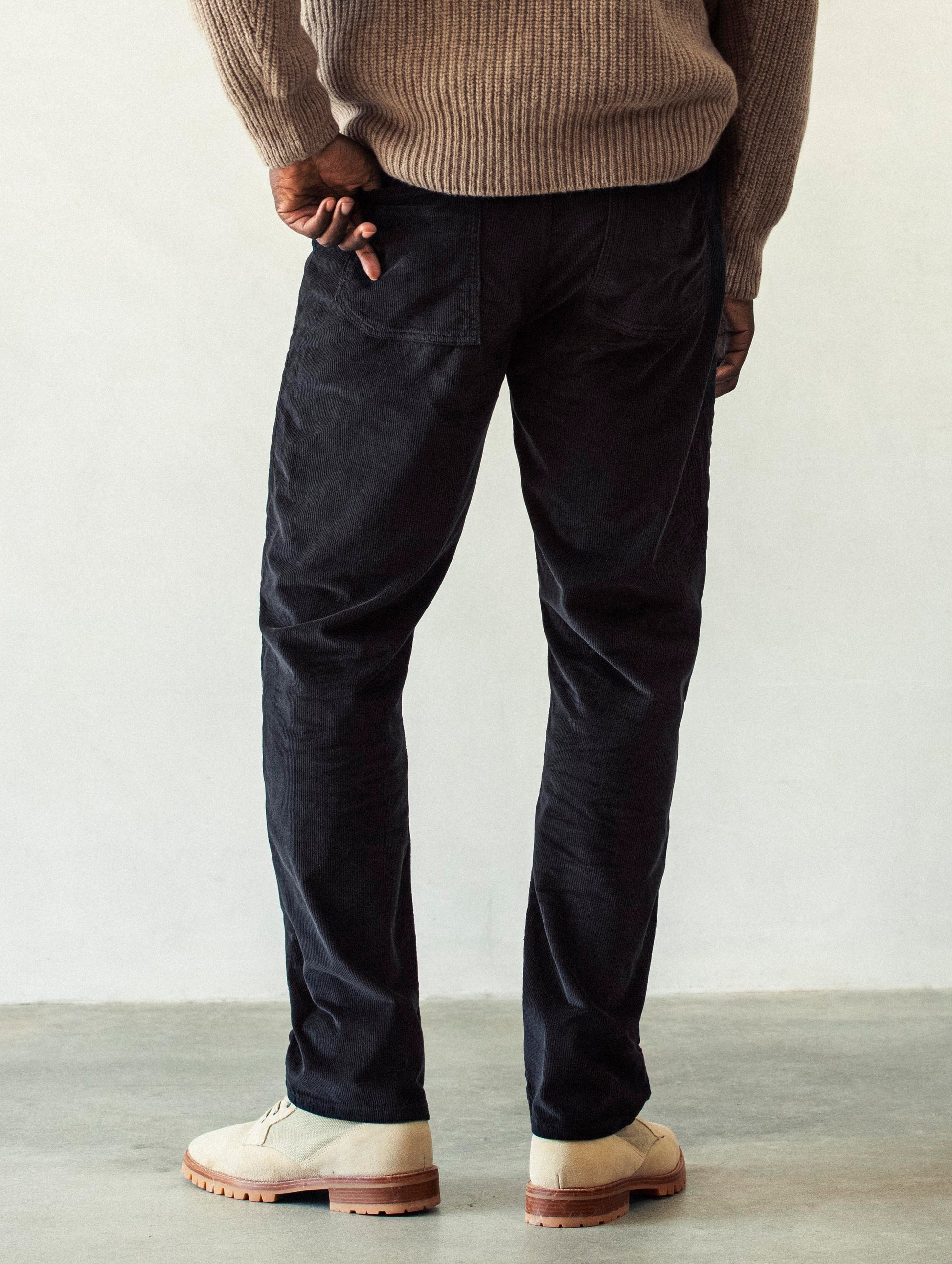 Rear lower body view of man wearing Hayden Corduroy Pant in Tarmac Black from AETHER Apparel.