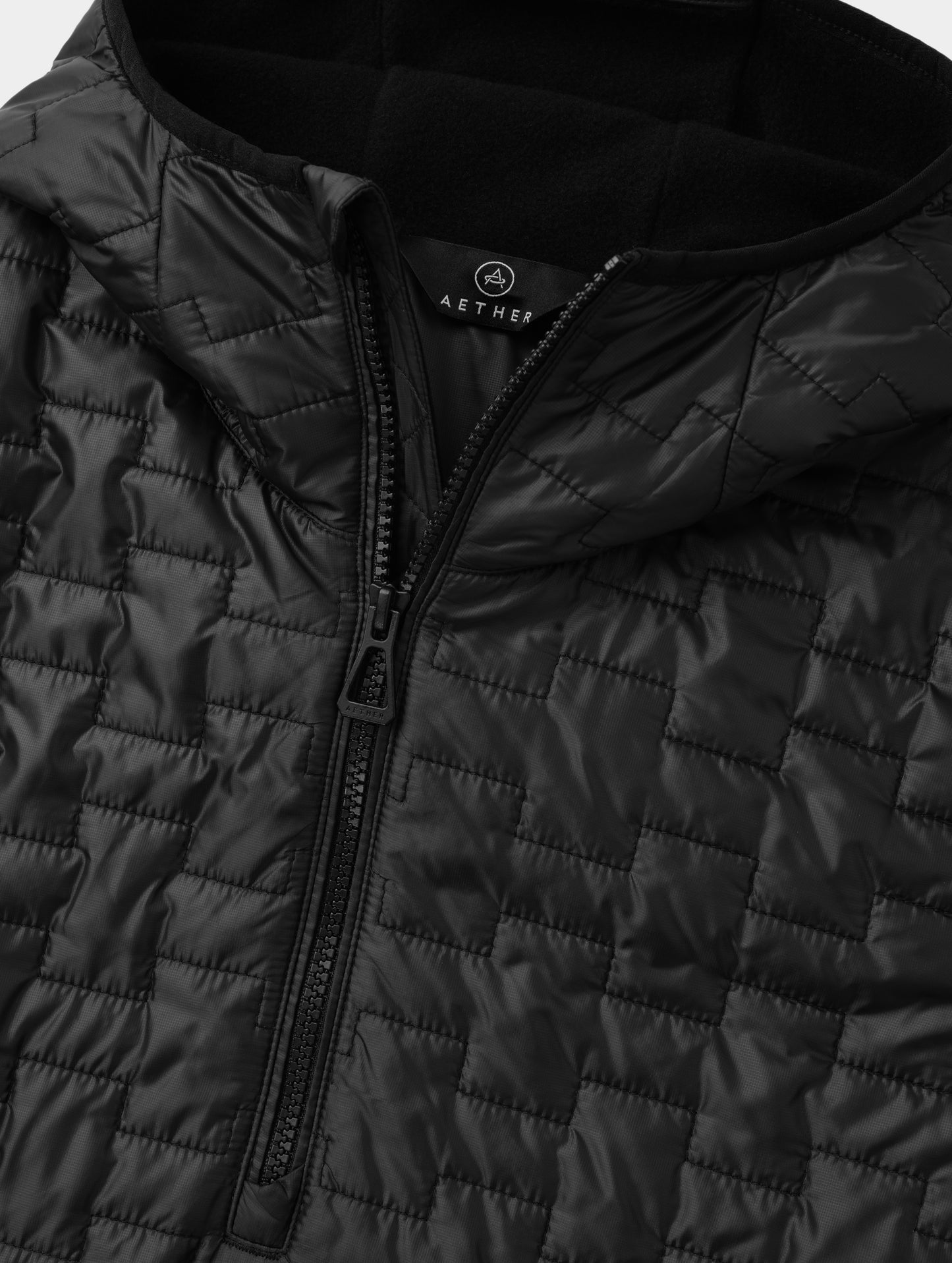 Closeup detailed flat lay view of the zipper and fleece-lined hood on the Hybrid Tech Anorak in Onyx Black from AETHER Apparel. 