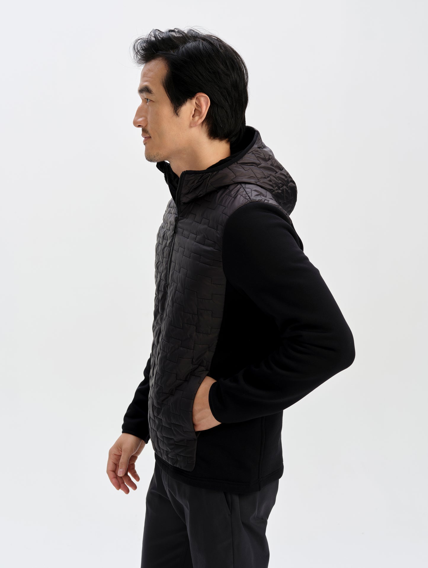 Side profile upper-body view of man wearing the Hybrid Tech Anorak in Onyx Black from AETHER Apparel. 
