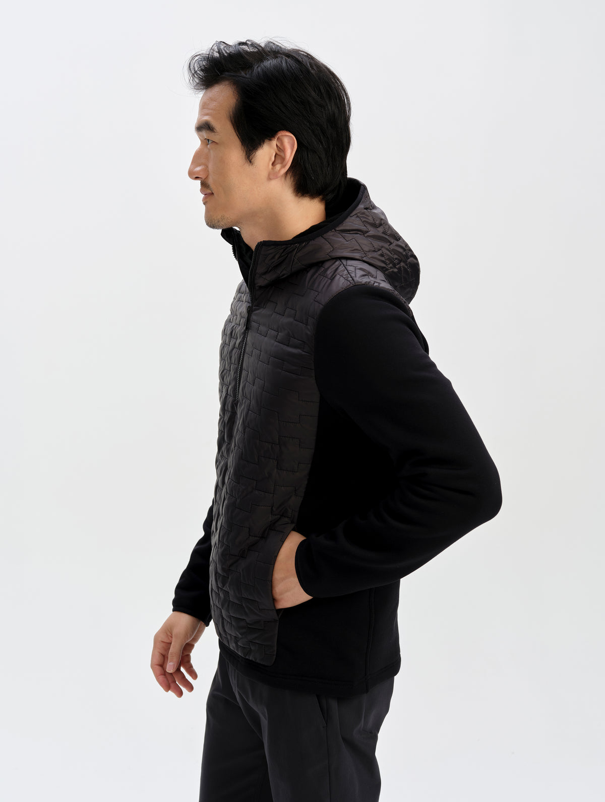 Side profile upper-body view of man wearing the Hybrid Tech Anorak in Onyx Black from AETHER Apparel. 