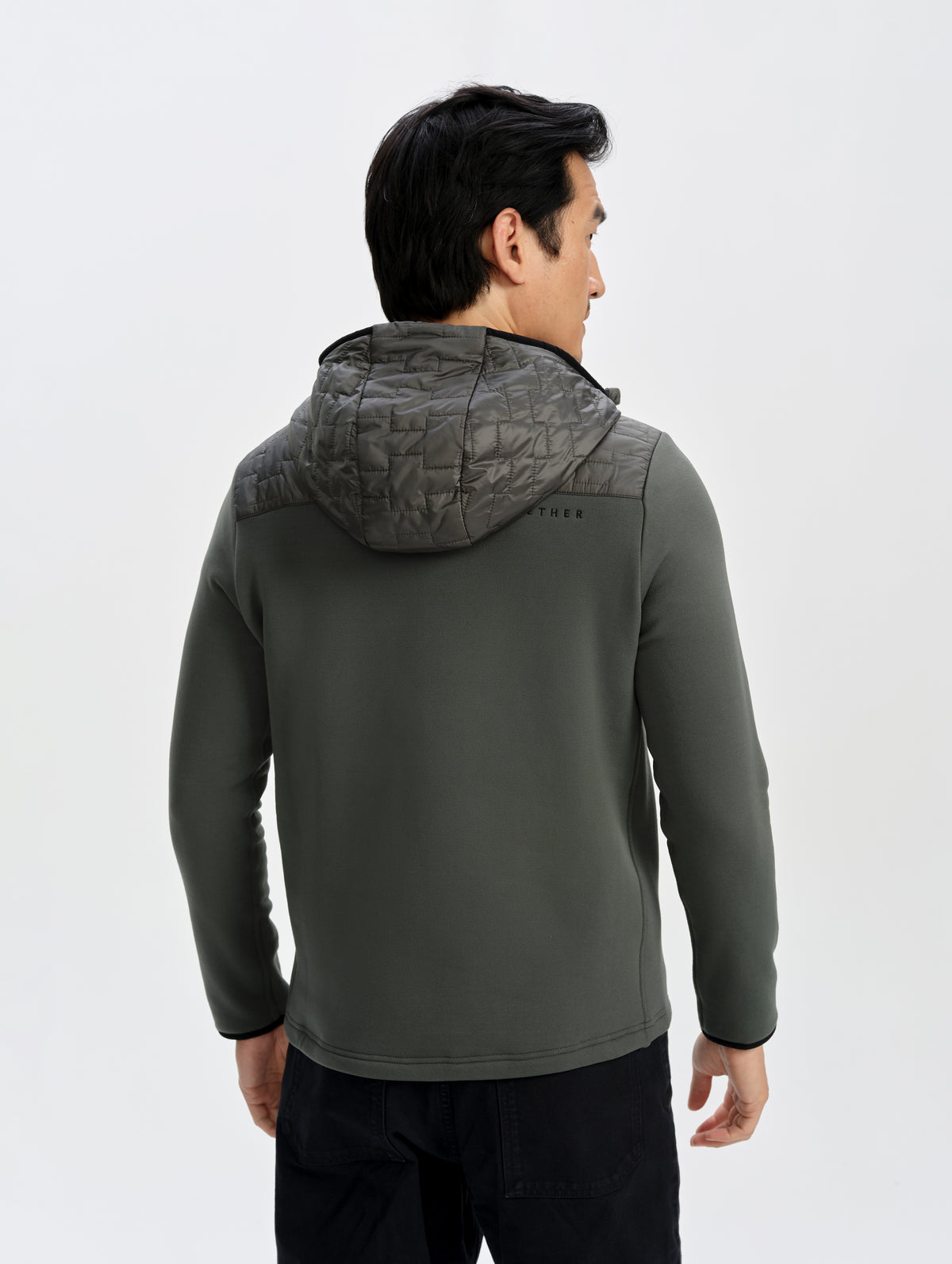 Rear upper-body view of man wearing the Hybrid Tech Anorak in Saville Green from AETHER Apparel. 
