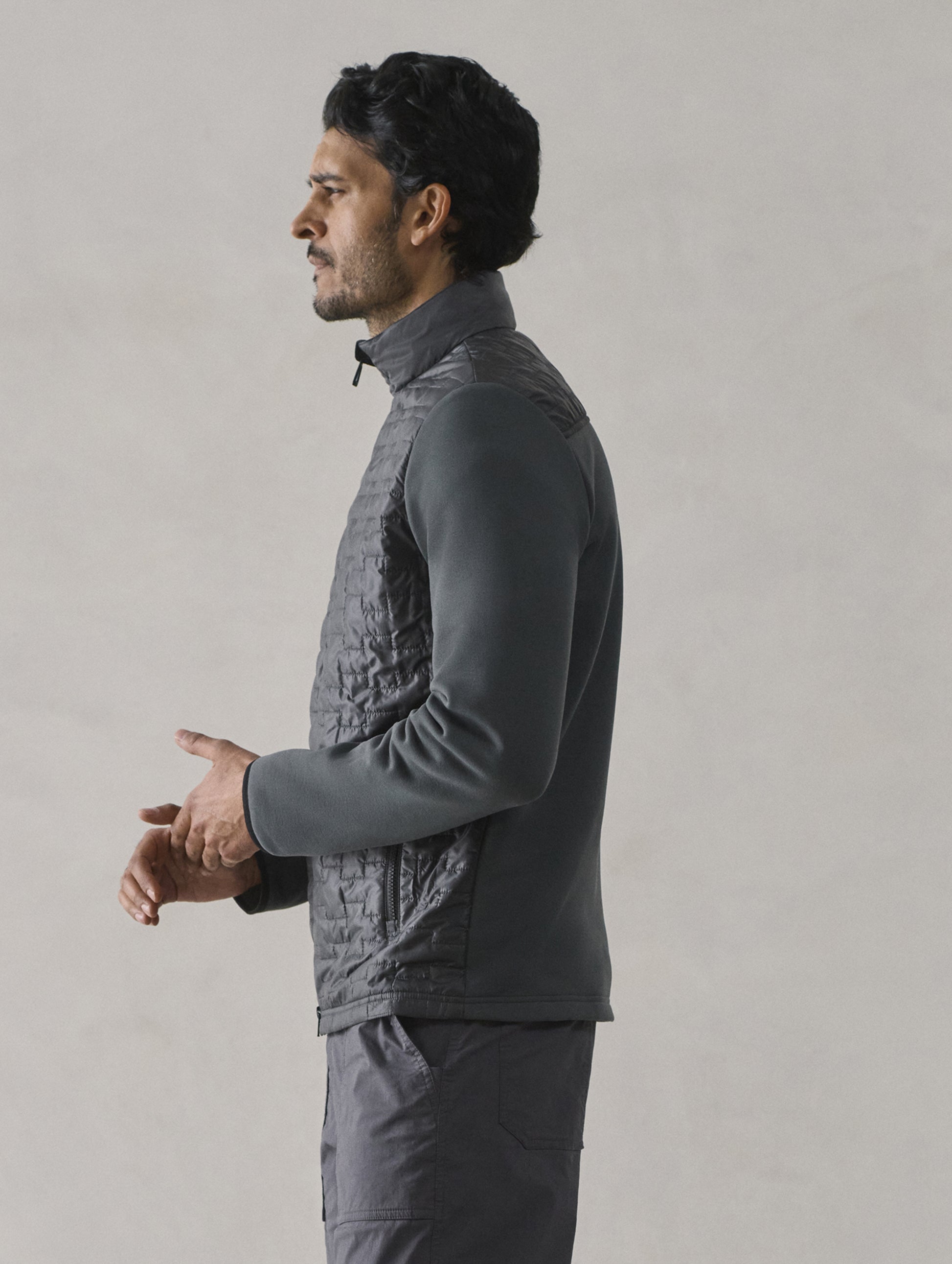 Side profile view of man wearing Hybrid Tech Full-Zip in Graphite from AETHER Apparel.