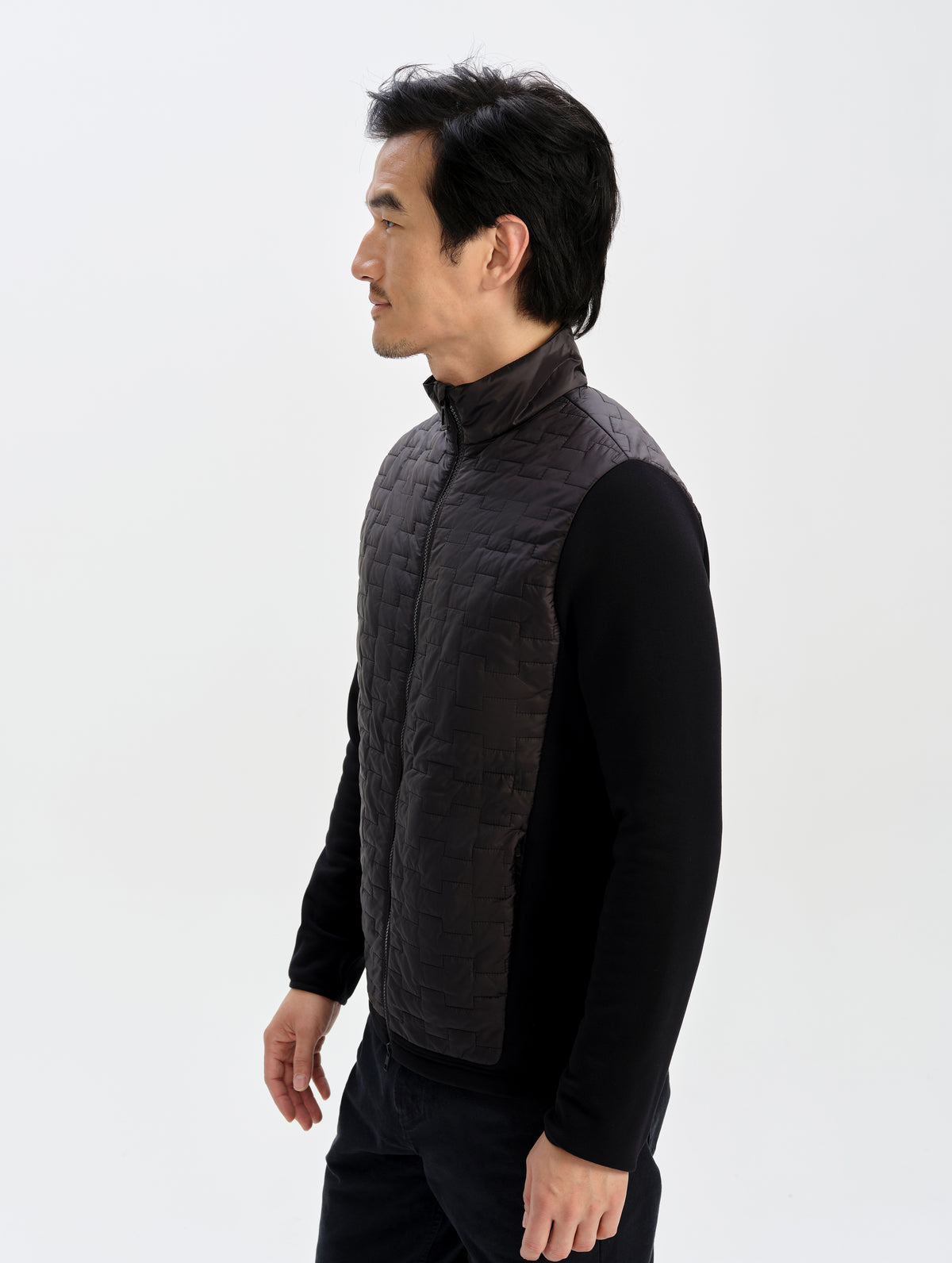 Side profile upper-body view of man wearing the Hybrid Tech Full-Zip 2.0 in Onyx Black from AETHER Apparel. 