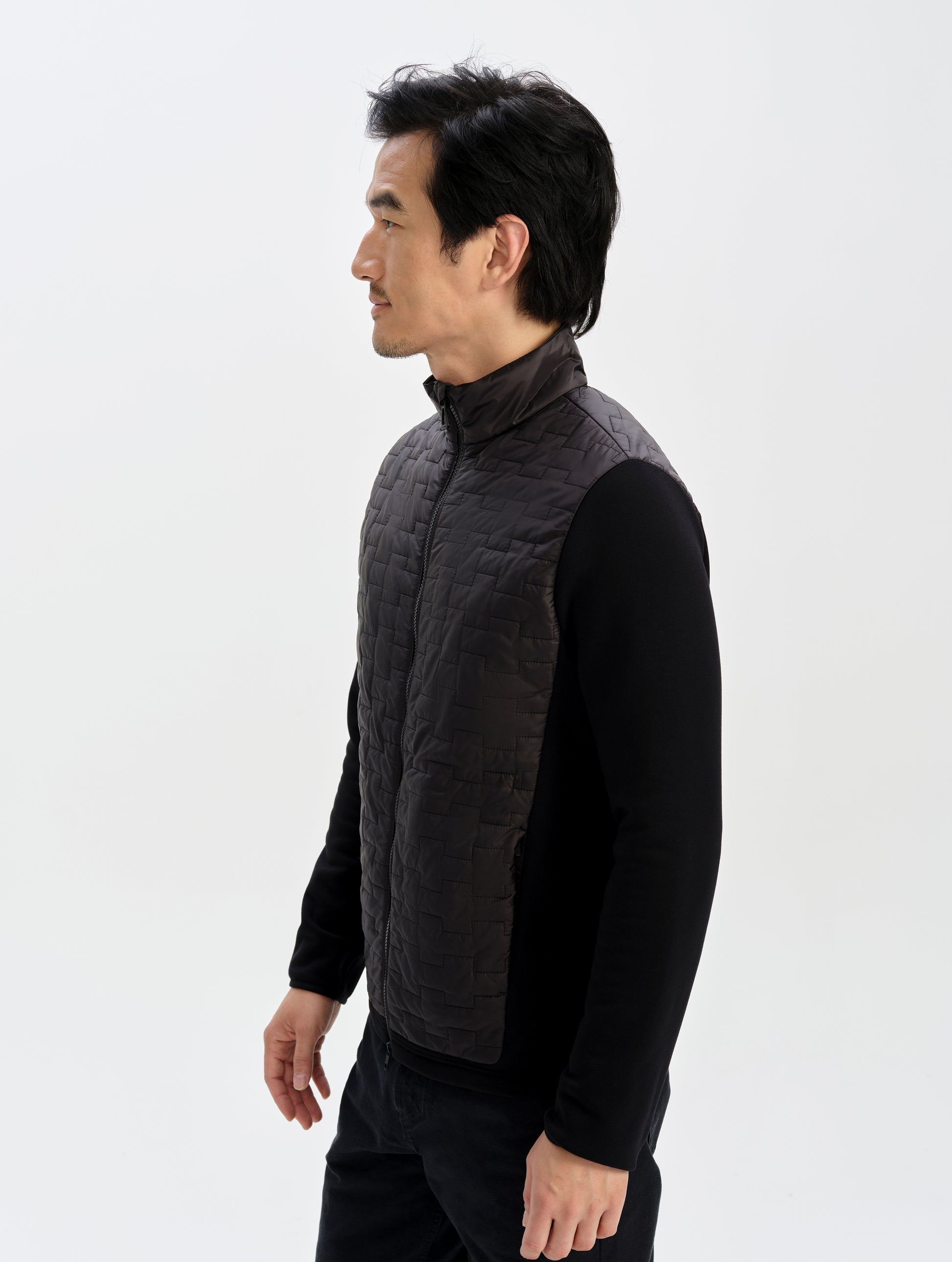 Side profile upper-body view of man wearing the Hybrid Tech Full-Zip 2.0 in Onyx Black from AETHER Apparel. 