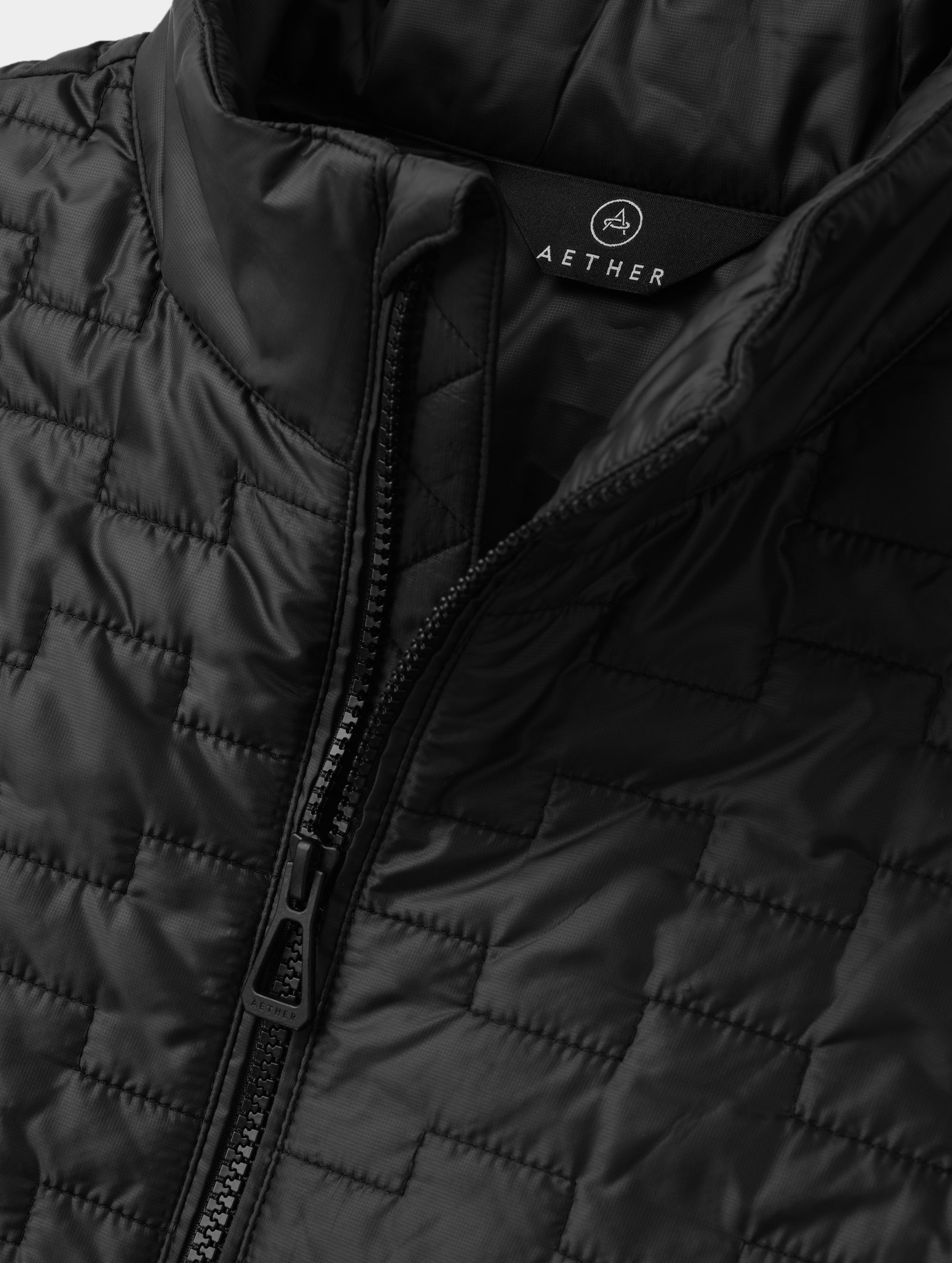 Closeup detailed view of the main center-front zipper on the Hybrid Tech Full-Zip 2.0 in Onyx Black from AETHER Apparel. 