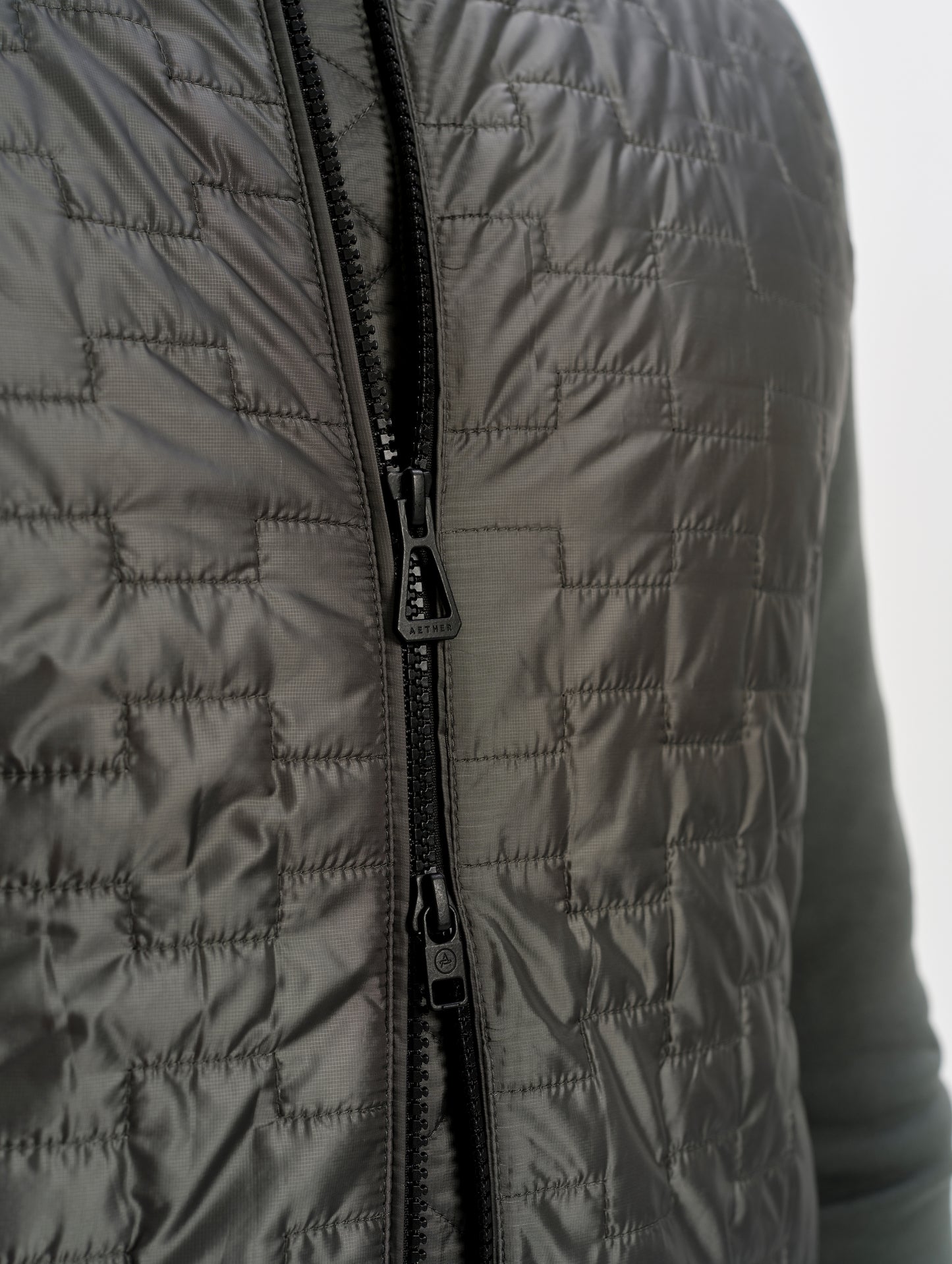 Closeup detailed view of the two-way center-front zipper on the Hybrid Tech Full-Zip 2.0 in Saville Green from AETHER Apparel. 