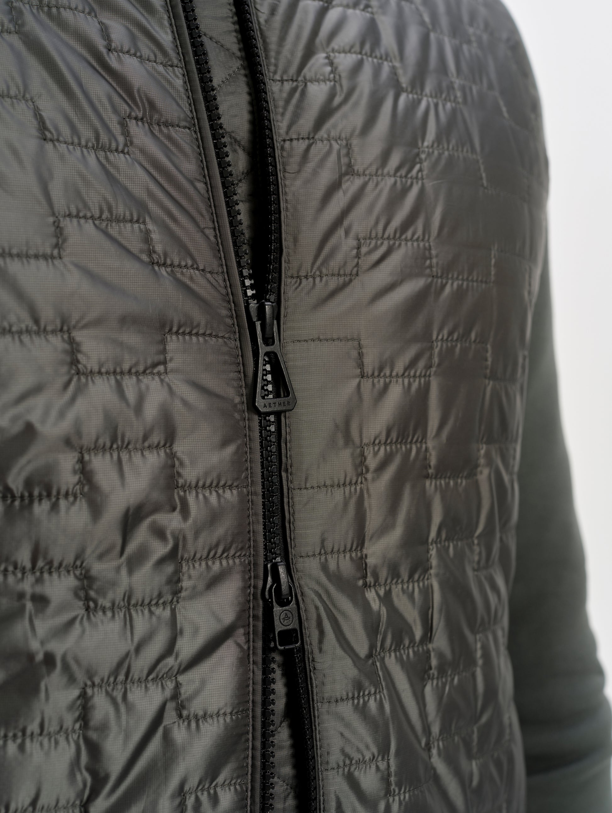 Closeup detailed view of the two-way center-front zipper on the Hybrid Tech Full-Zip 2.0 in Saville Green from AETHER Apparel. 