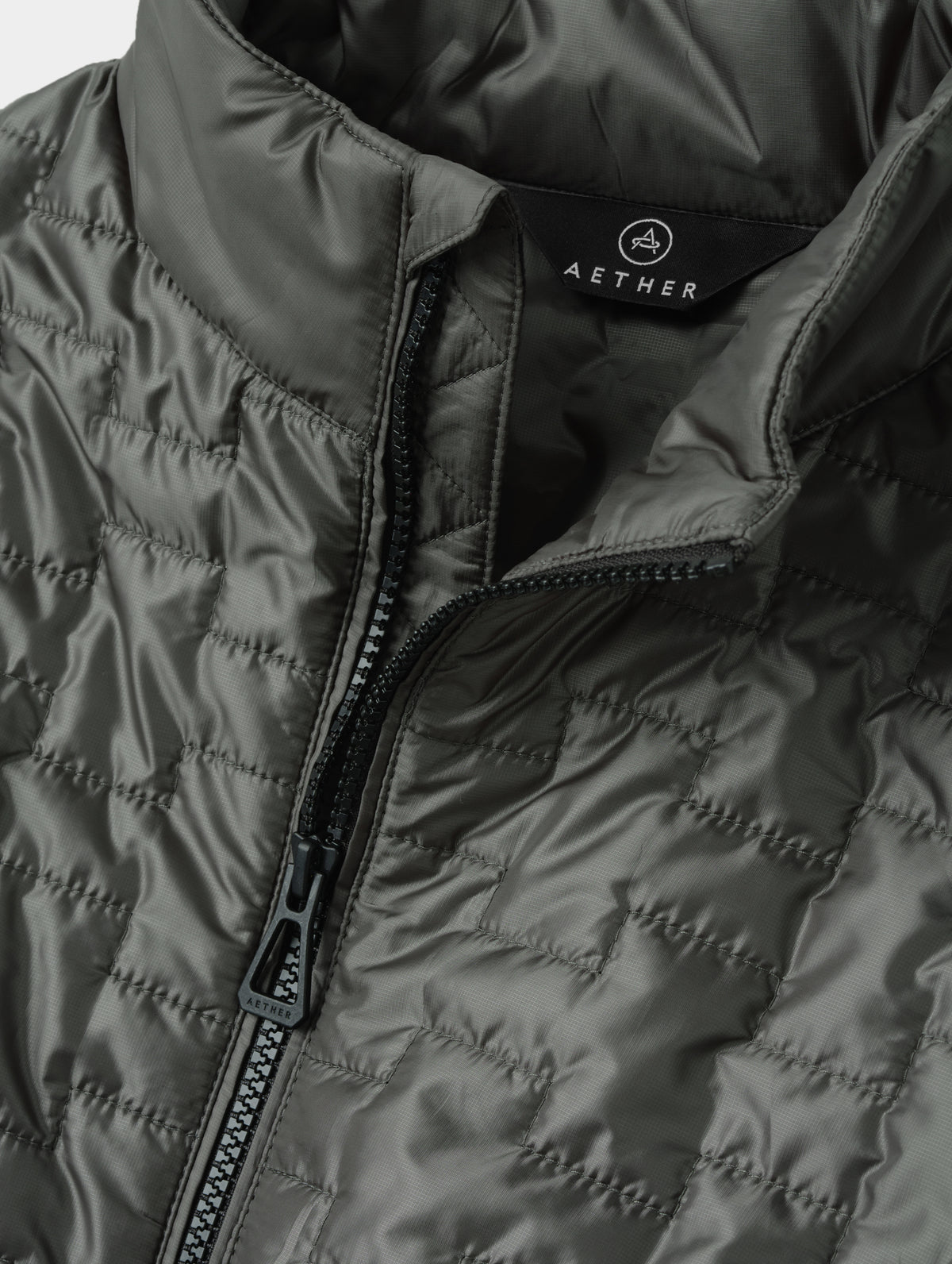 Closeup detailed view of the main center-front zipper on the Hybrid Tech Full-Zip 2.0 in Saville Green from AETHER Apparel. 