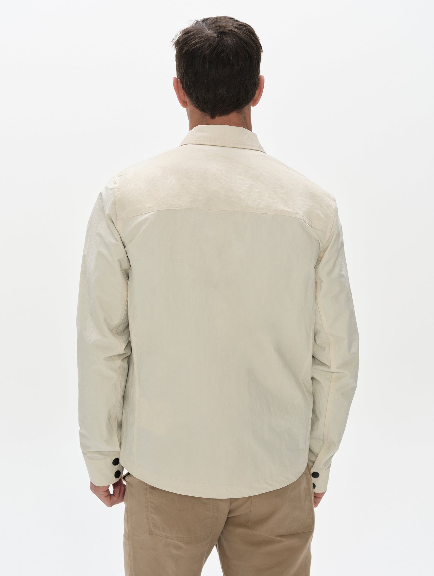 Rear, upper-body view of man wearing the Landon Jacket in Onyx Black from AETHER Apparel.