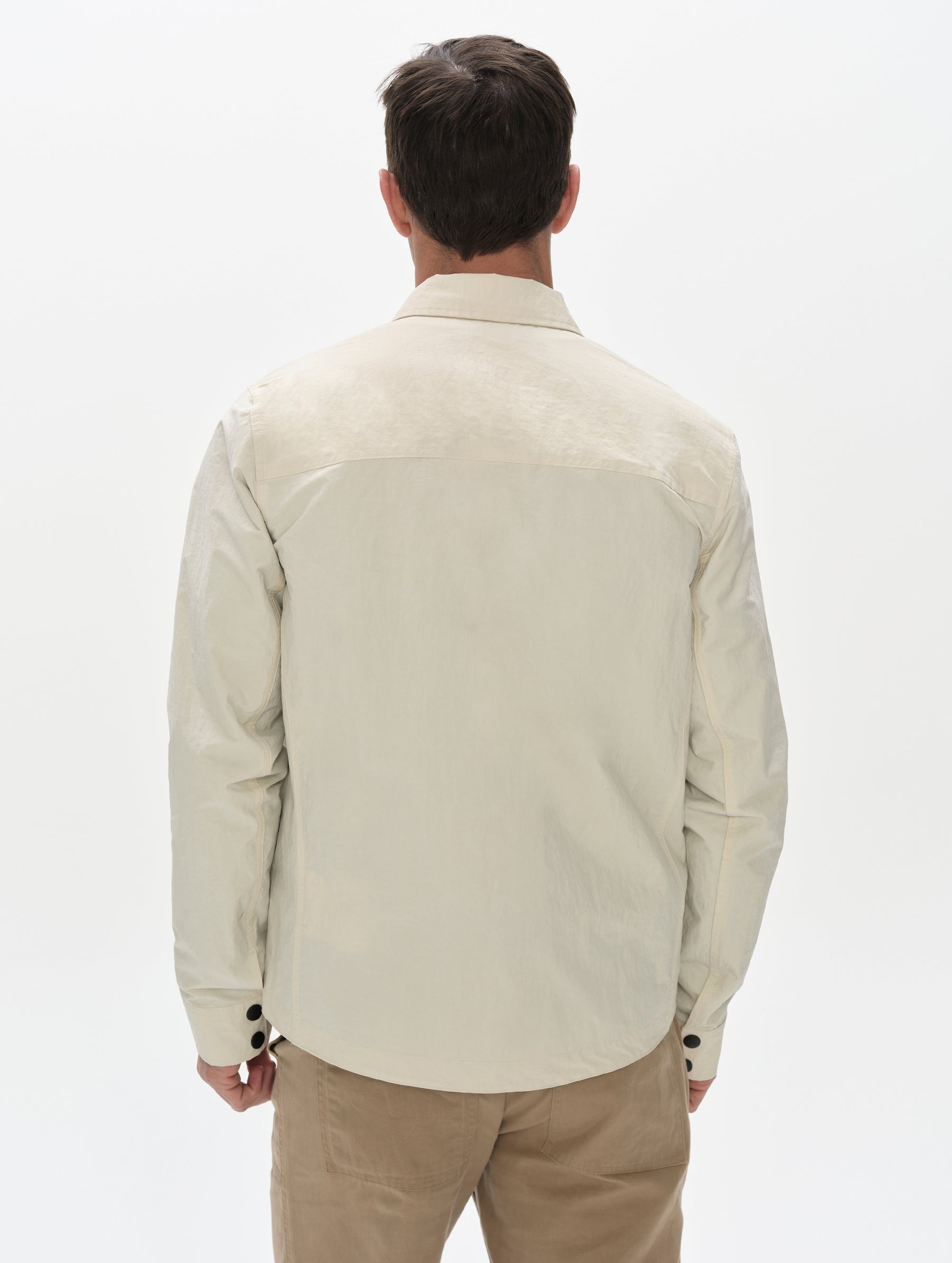 Rear, upper-body view of man wearing the Landon Jacket in Onyx Black from AETHER Apparel.