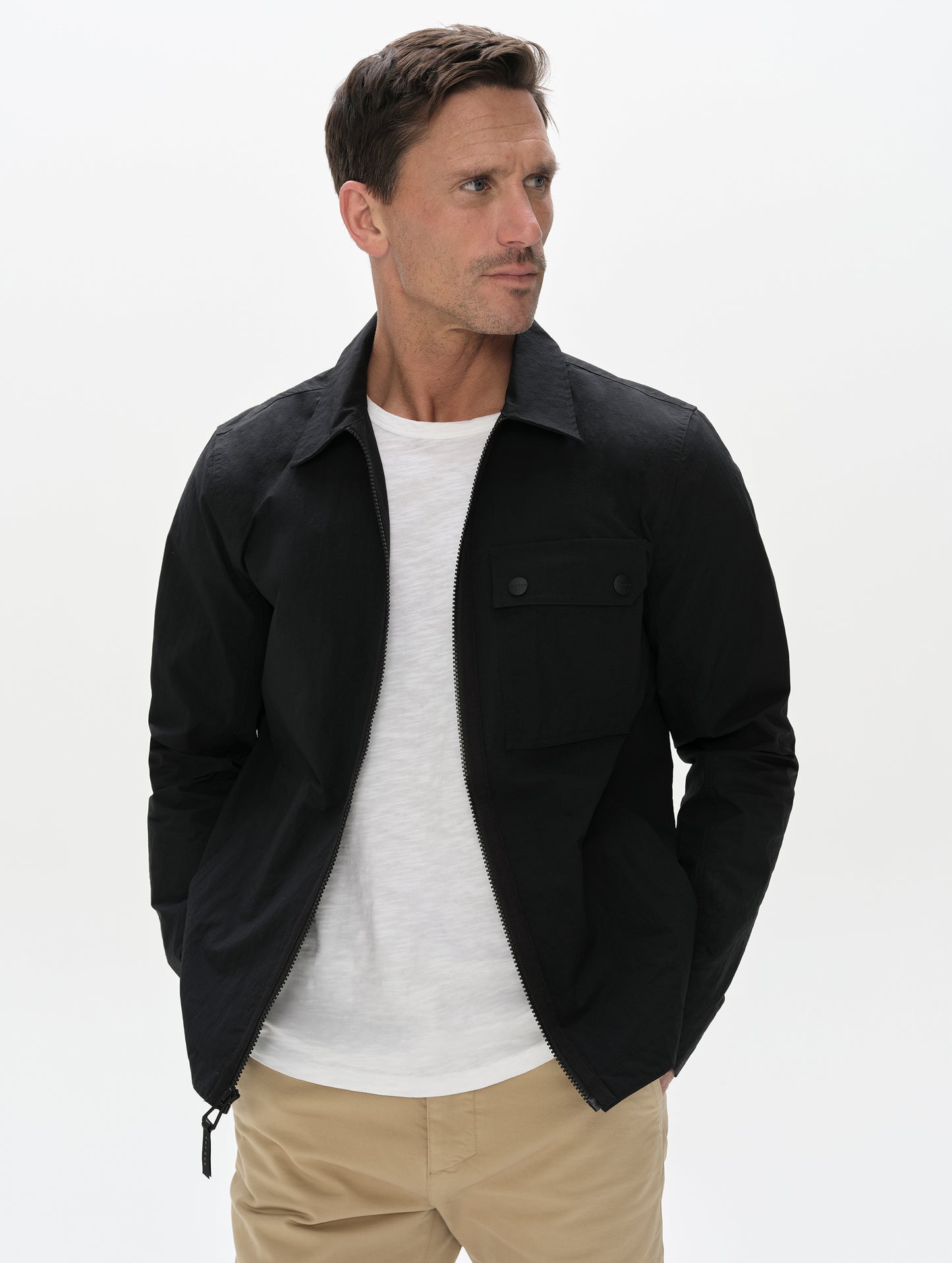 Front, upper-body view of man wearing the Landon Jacket in Onyx Black from AETHER Apparel unzipped. 