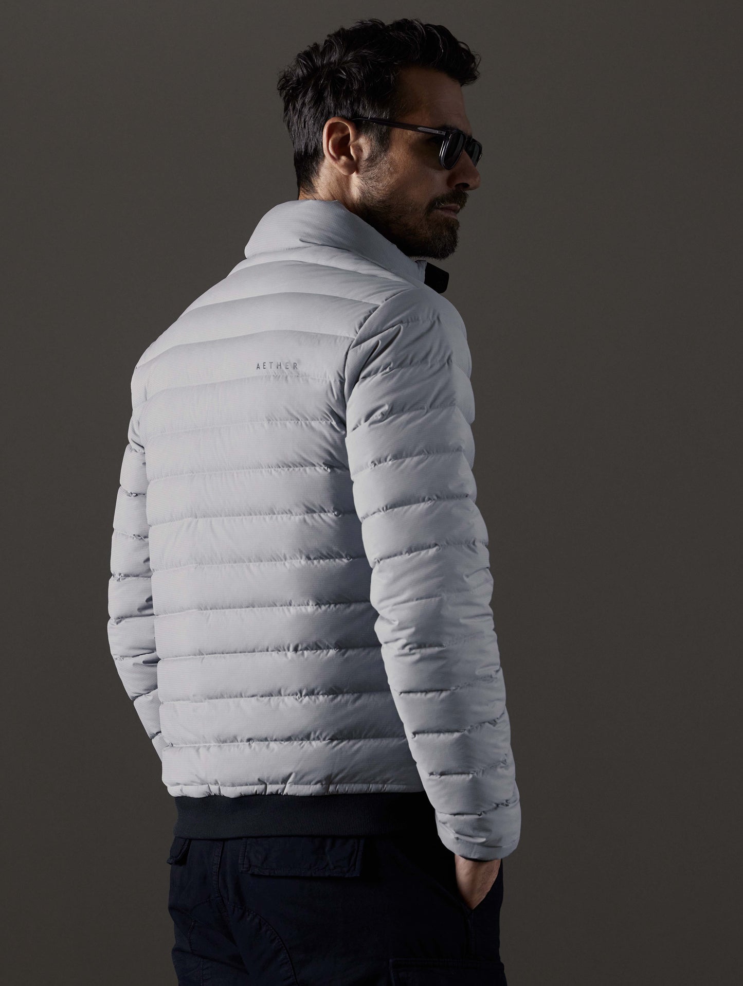 Rear 3/4 body view of man wearing Launch Full-Zip Jacket NH in Sky Grey from AETHER Apparel.