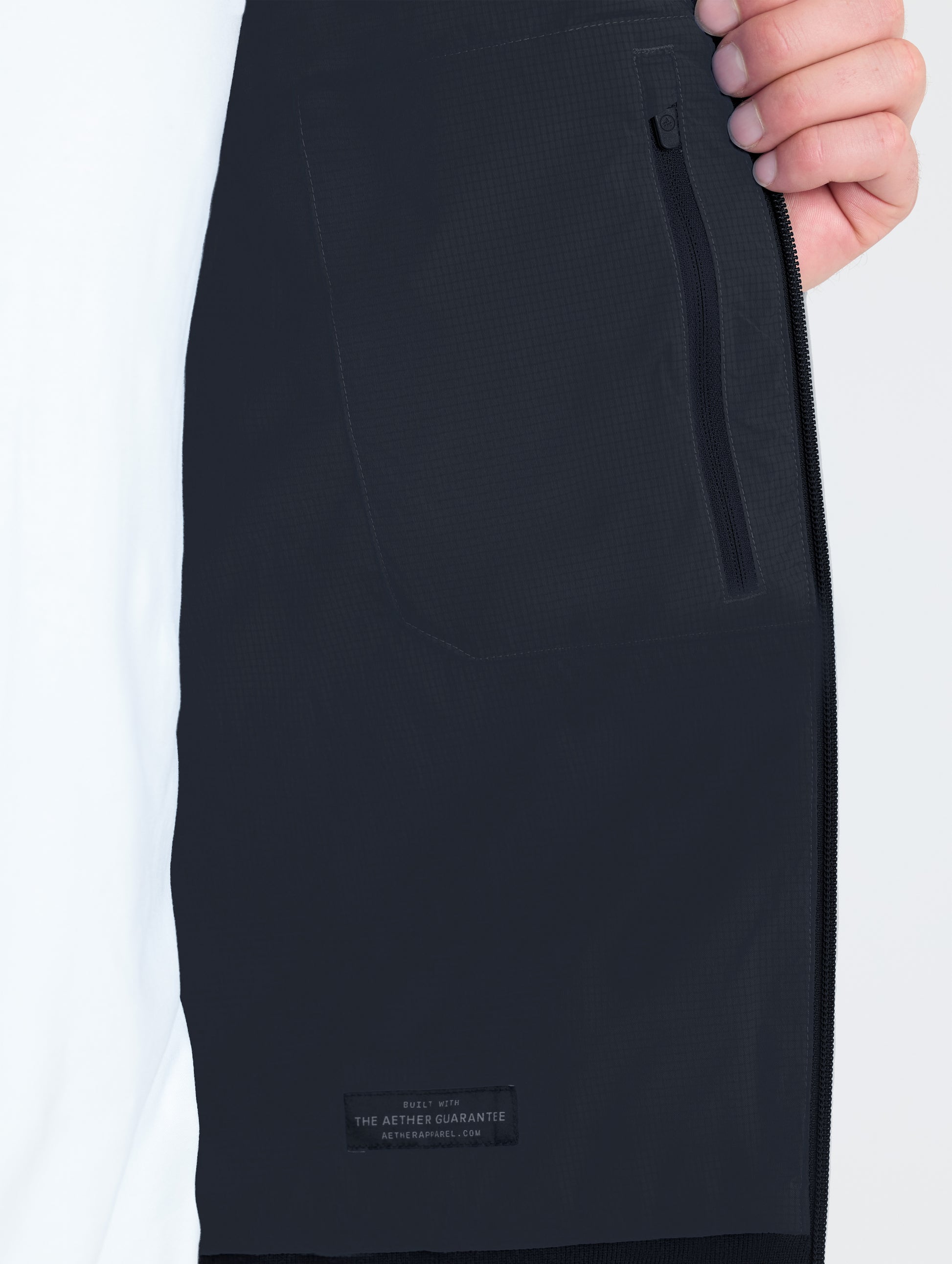 Closeup view of wearer's interior left zipped pocket of Launch Jacket in Onyx Black from AETHER Apparel.
