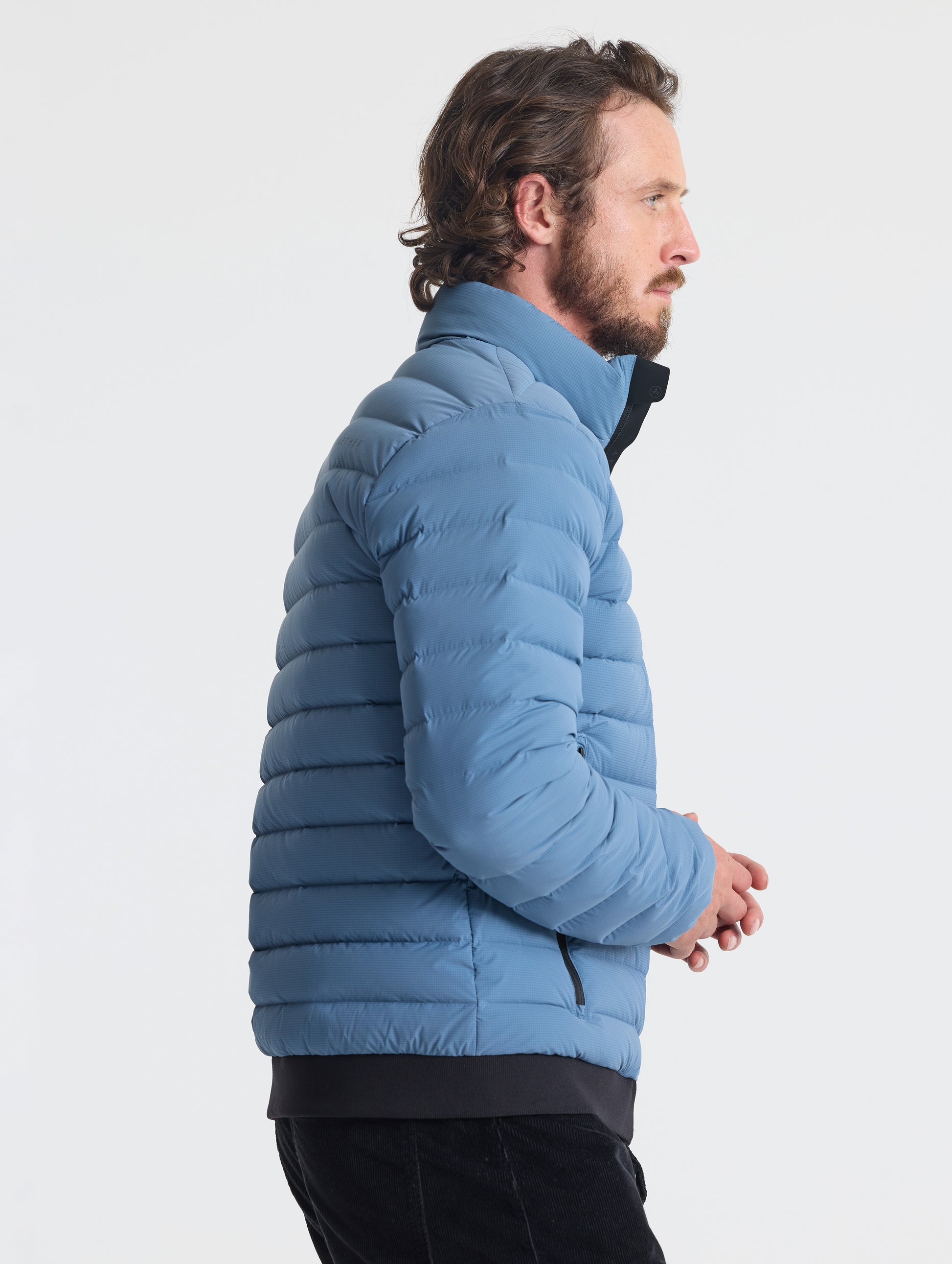 Right profile of man wearing Prospect Packable Down Jacket in Portal Blue from AETHER Apparel.