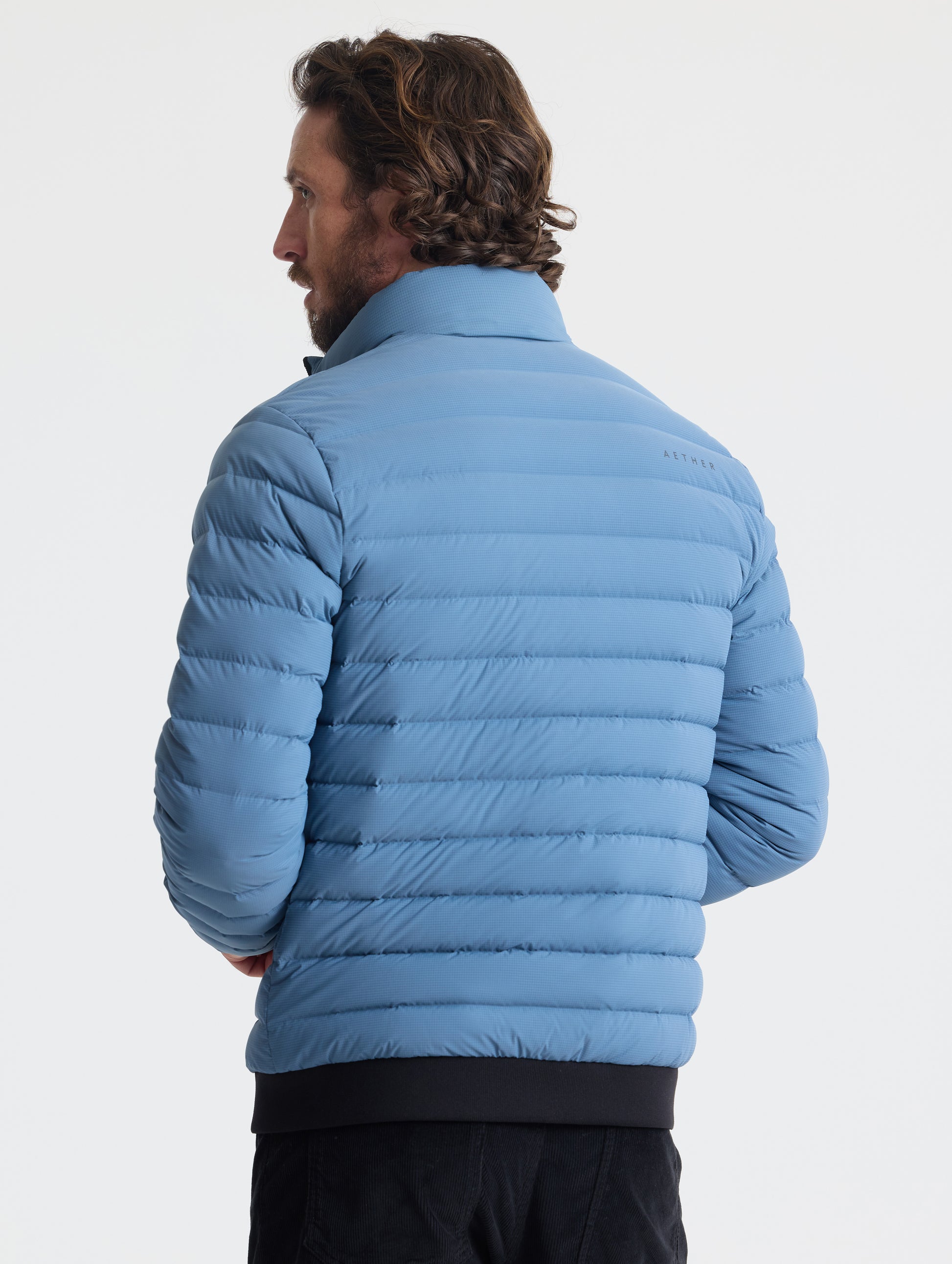 Rear view of man wearing Prospect Packable Down Jacket in Portal Blue from AETHER Apparel.