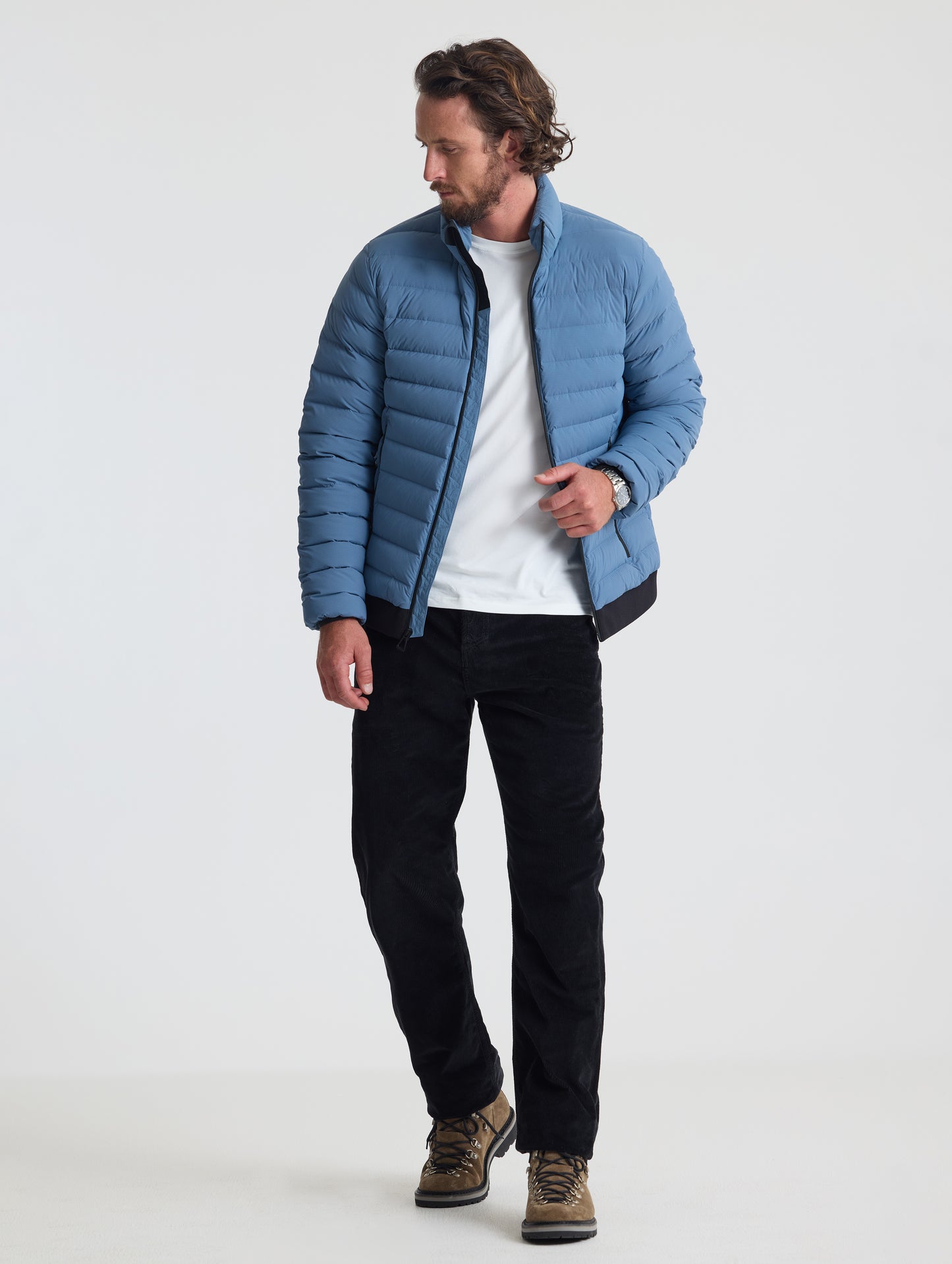 Full body view of man wearing Prospect Packable Down Jacket in Portal Blue from AETHER Apparel.