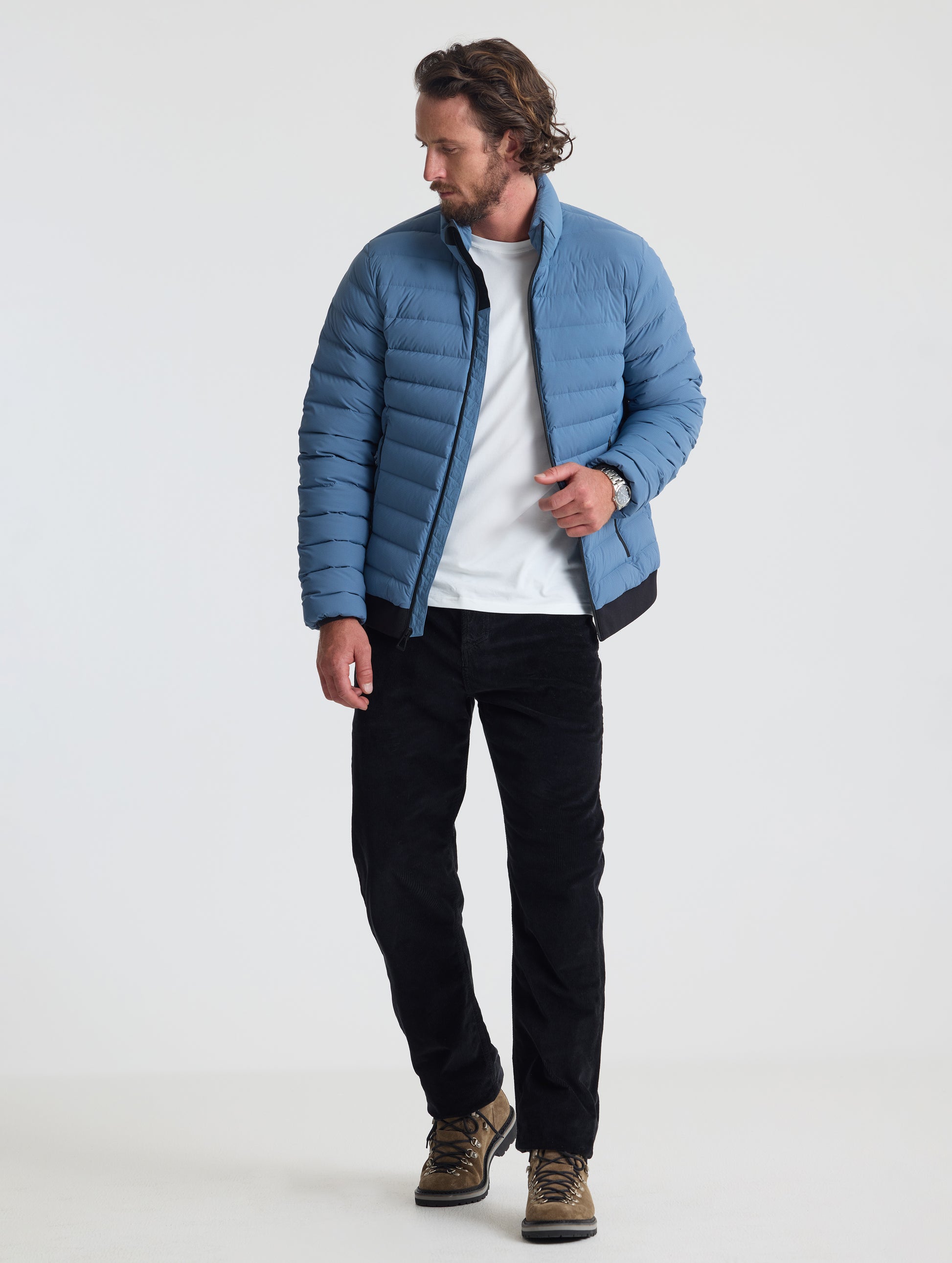 Full body view of man wearing Prospect Packable Down Jacket in Portal Blue from AETHER Apparel.