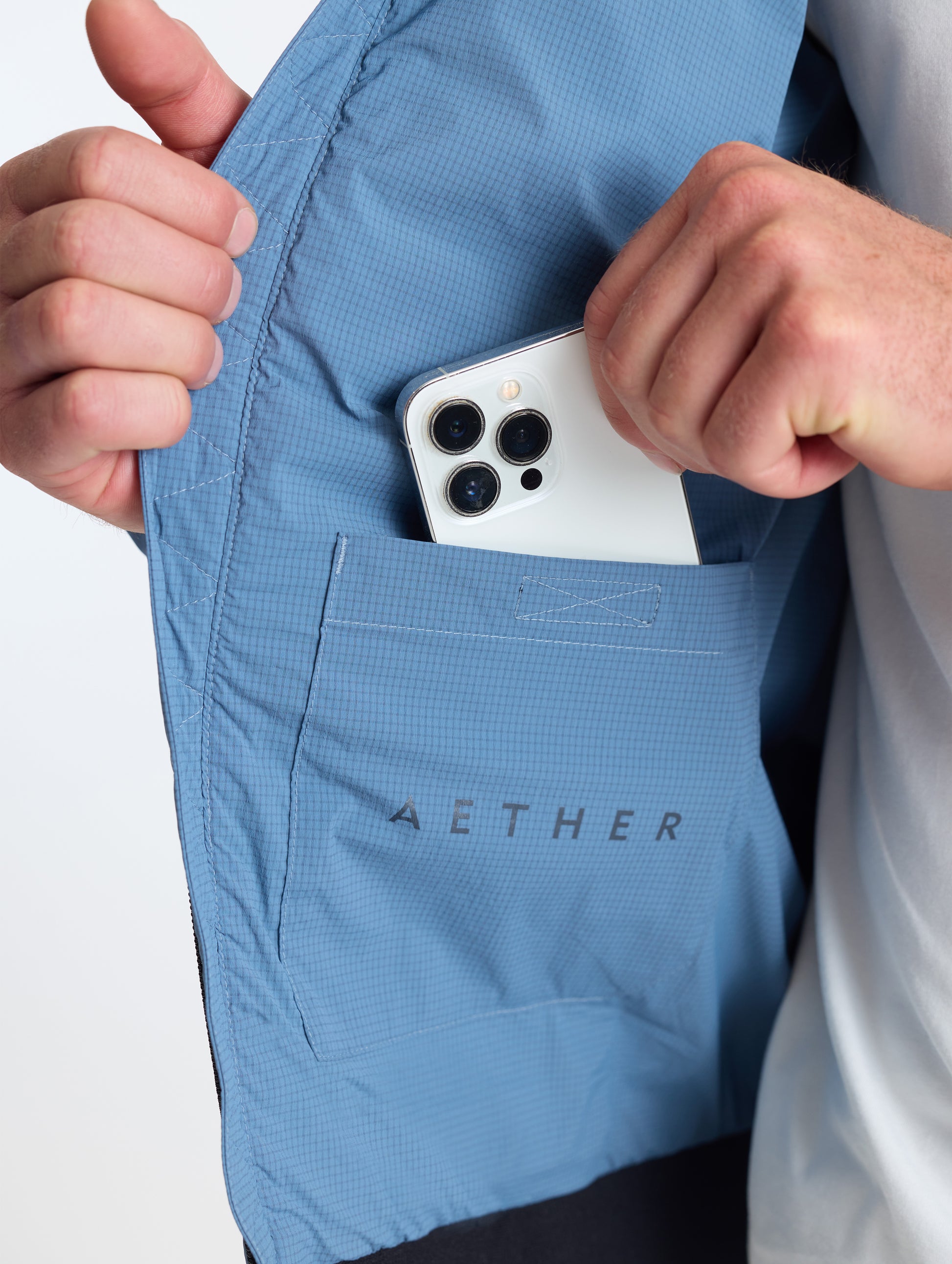 Closeup view of wearer's interior right drop pocket of Prospect Packable Down Jacket in Portal Blue from AETHER Apparel.