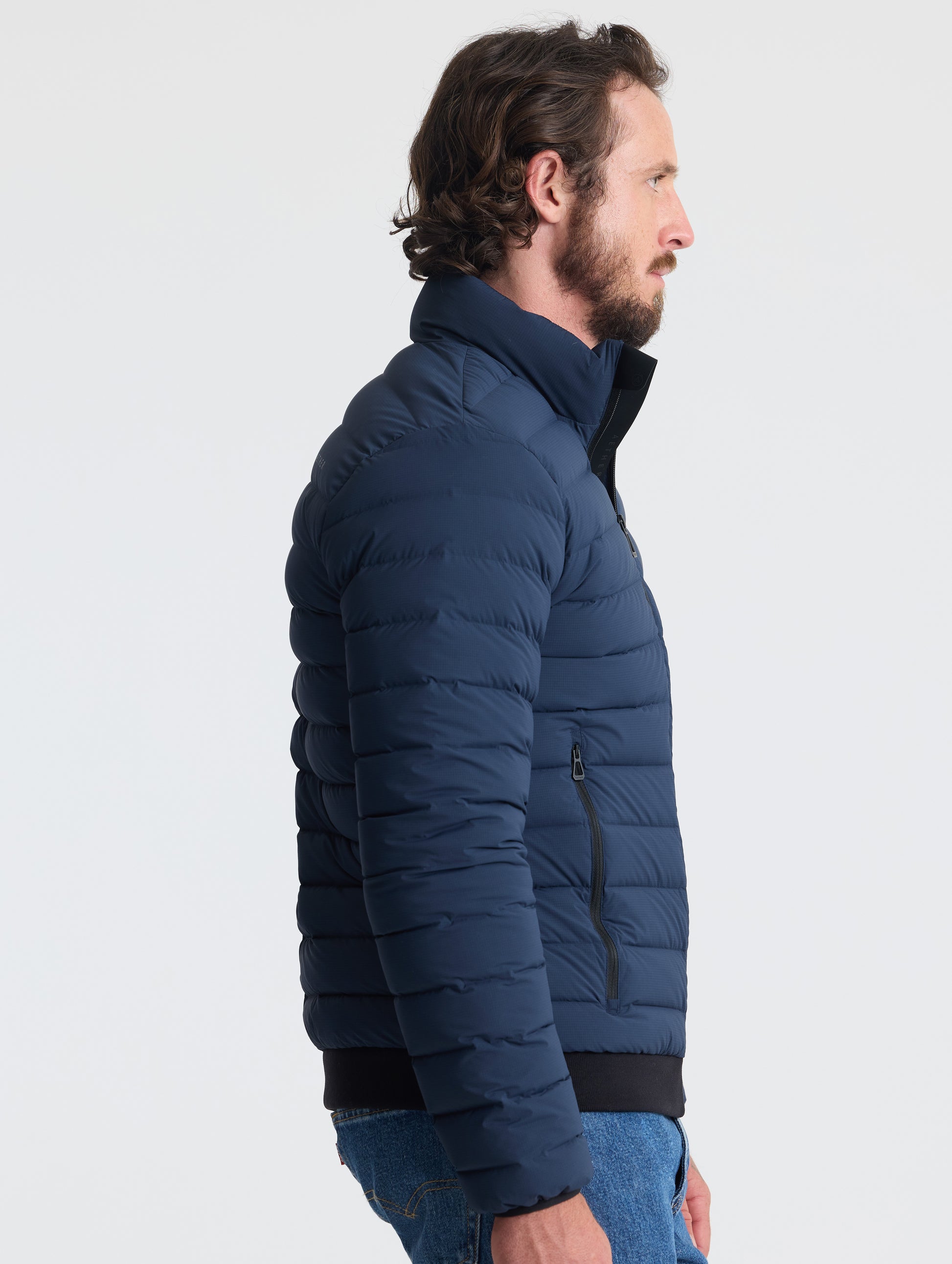 Right profile view of man wearing Launch Jacket in Total Eclipse dark blue from AETHER Apparel.