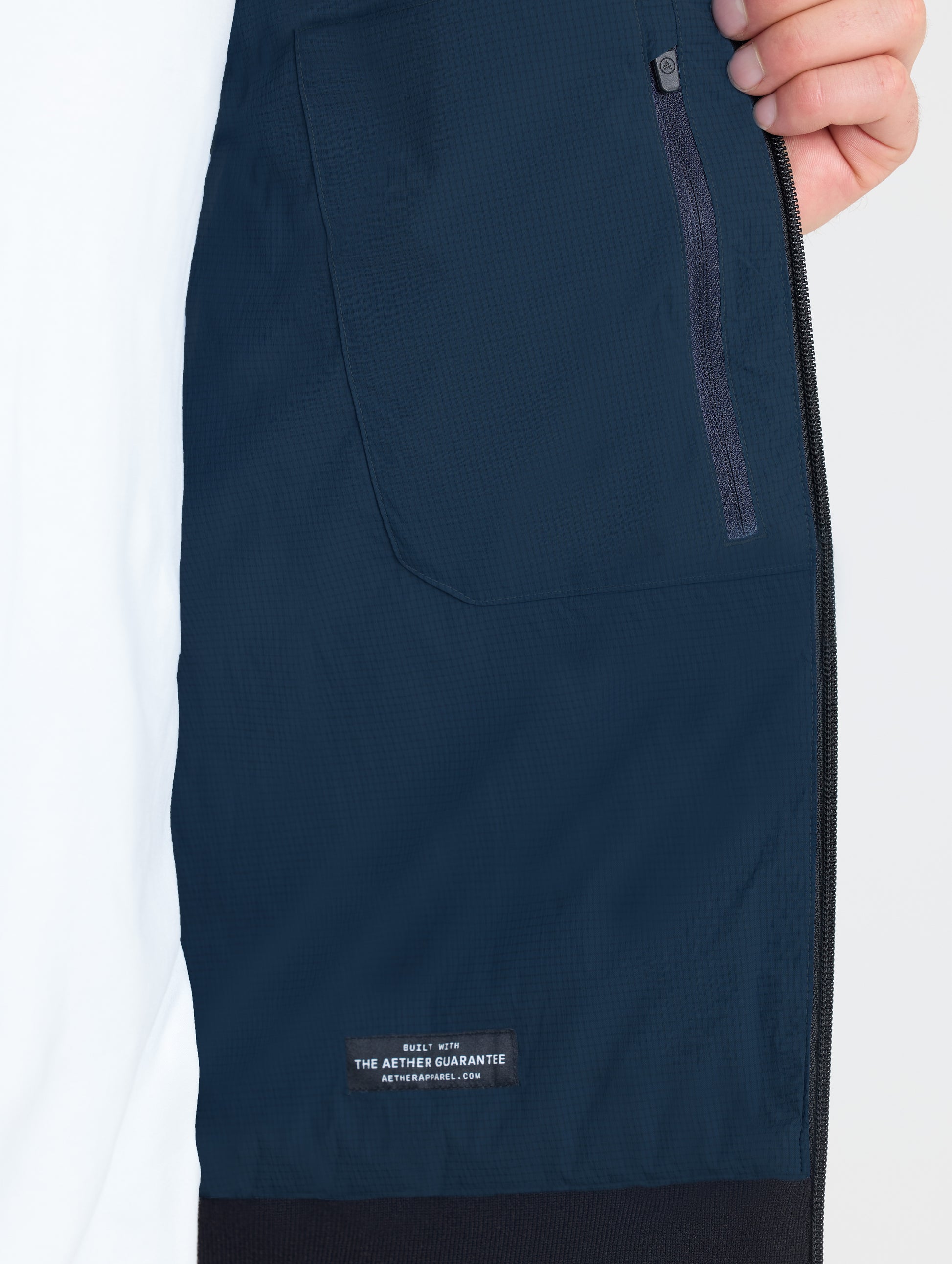 Closeup view of interior left zipped pocket of Launch Jacket in Total Eclipse dark blue from AETHER Apparel.
