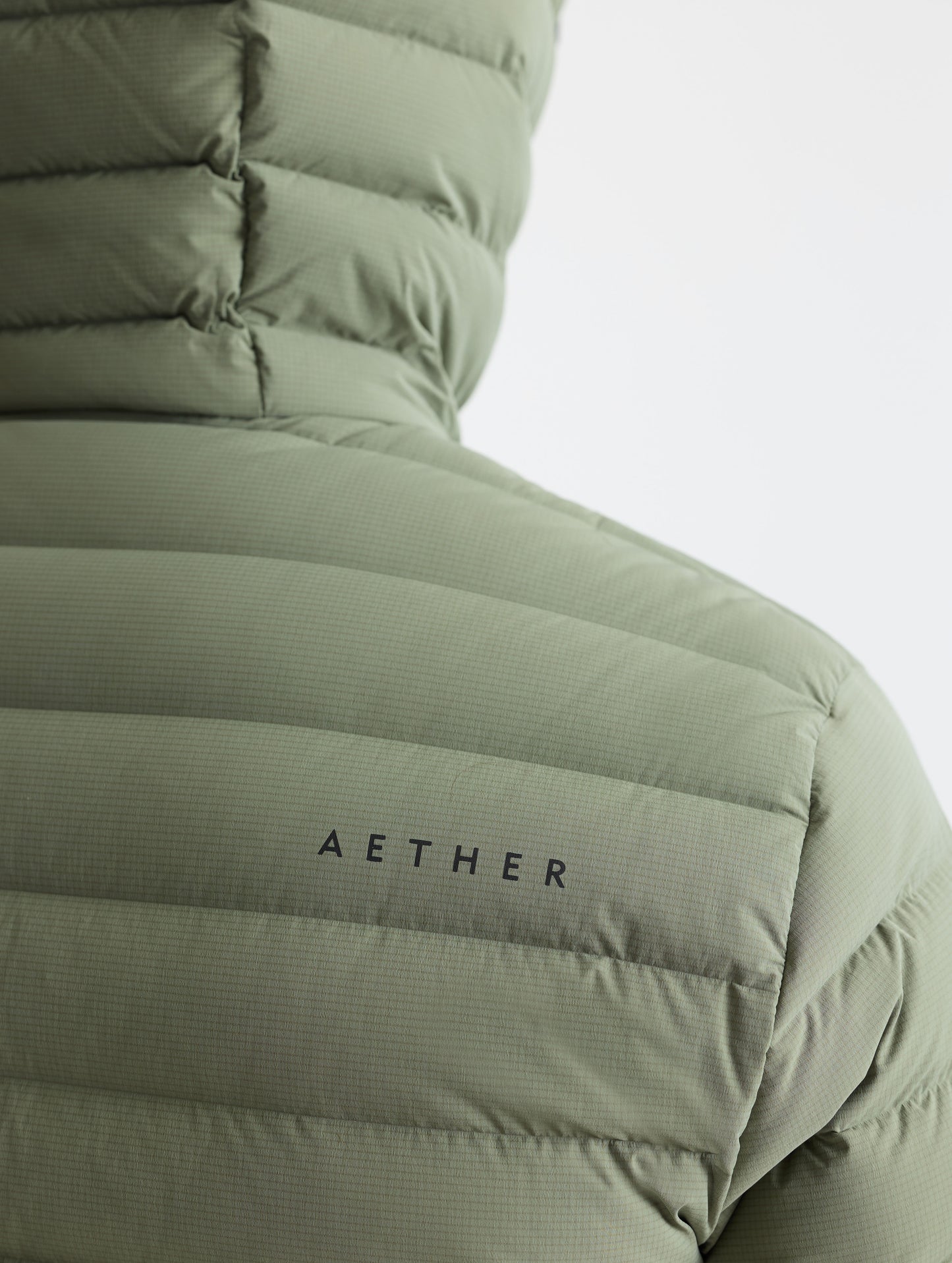 Closeup rear detail view of wearer's right shoulder of Launch Full-Zip Hooded Jacket in Fern Green from AETHER Apparel.