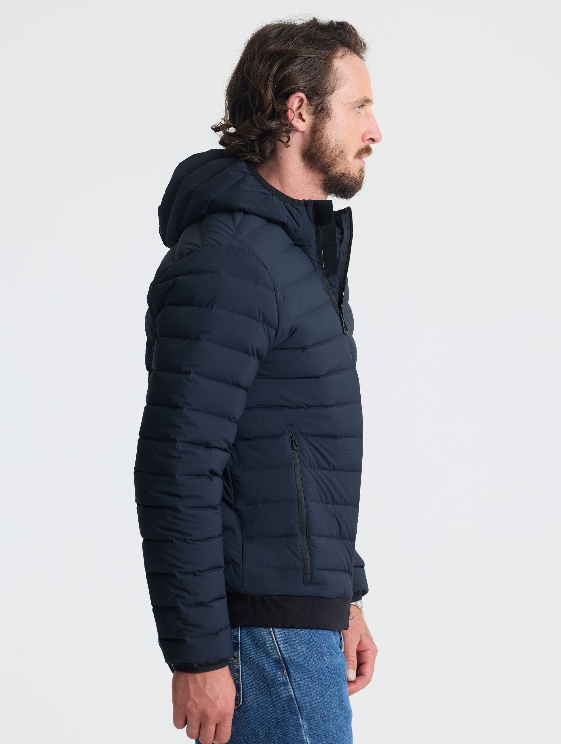 Right profile of man wearing Launch Full-Zip Hooded Jacket in Onyx Black from AETHER Apparel.

