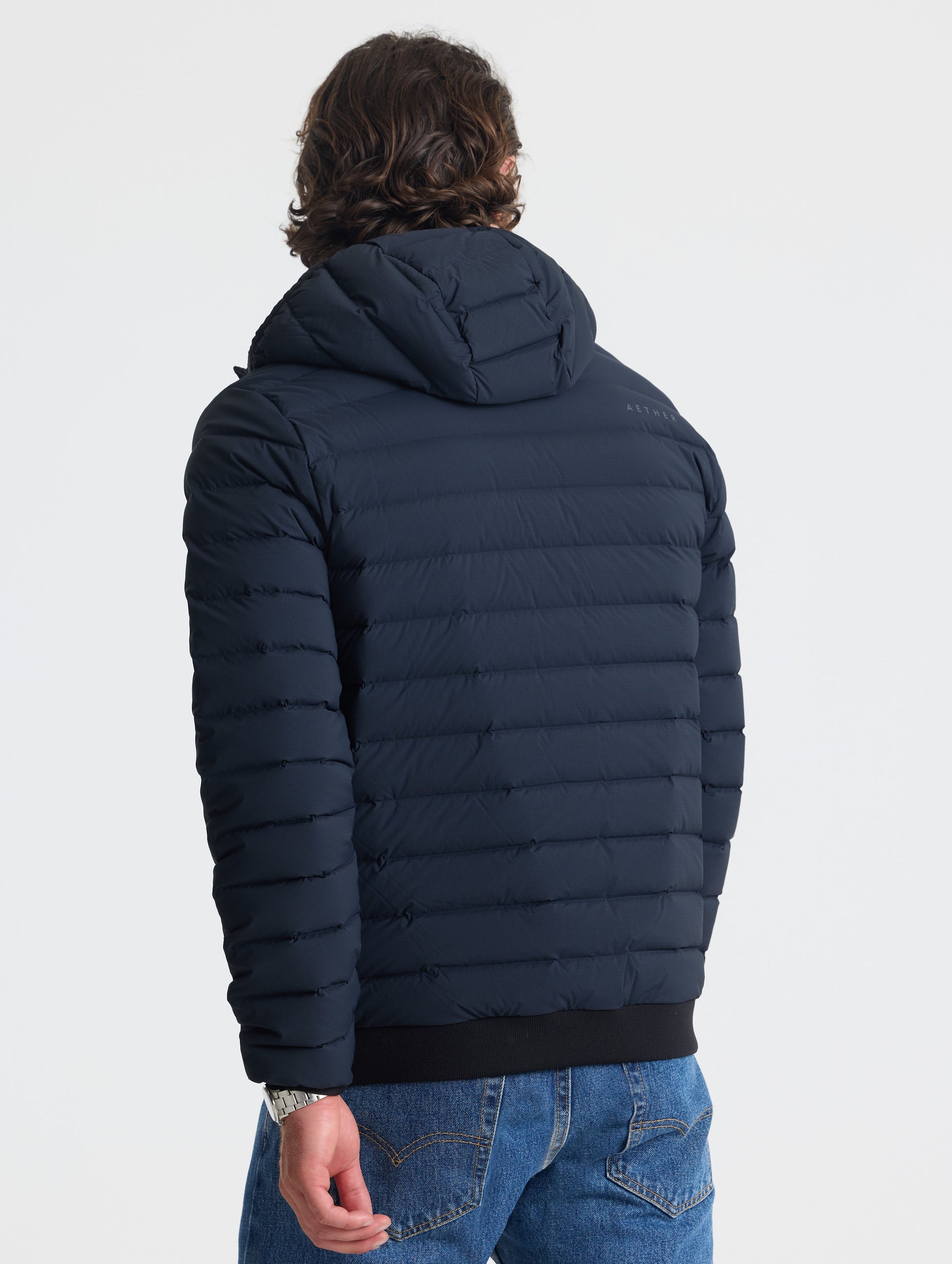 Rear view of man wearing Launch Full-Zip Hooded Jacket in Onyx Black from AETHER Apparel.

