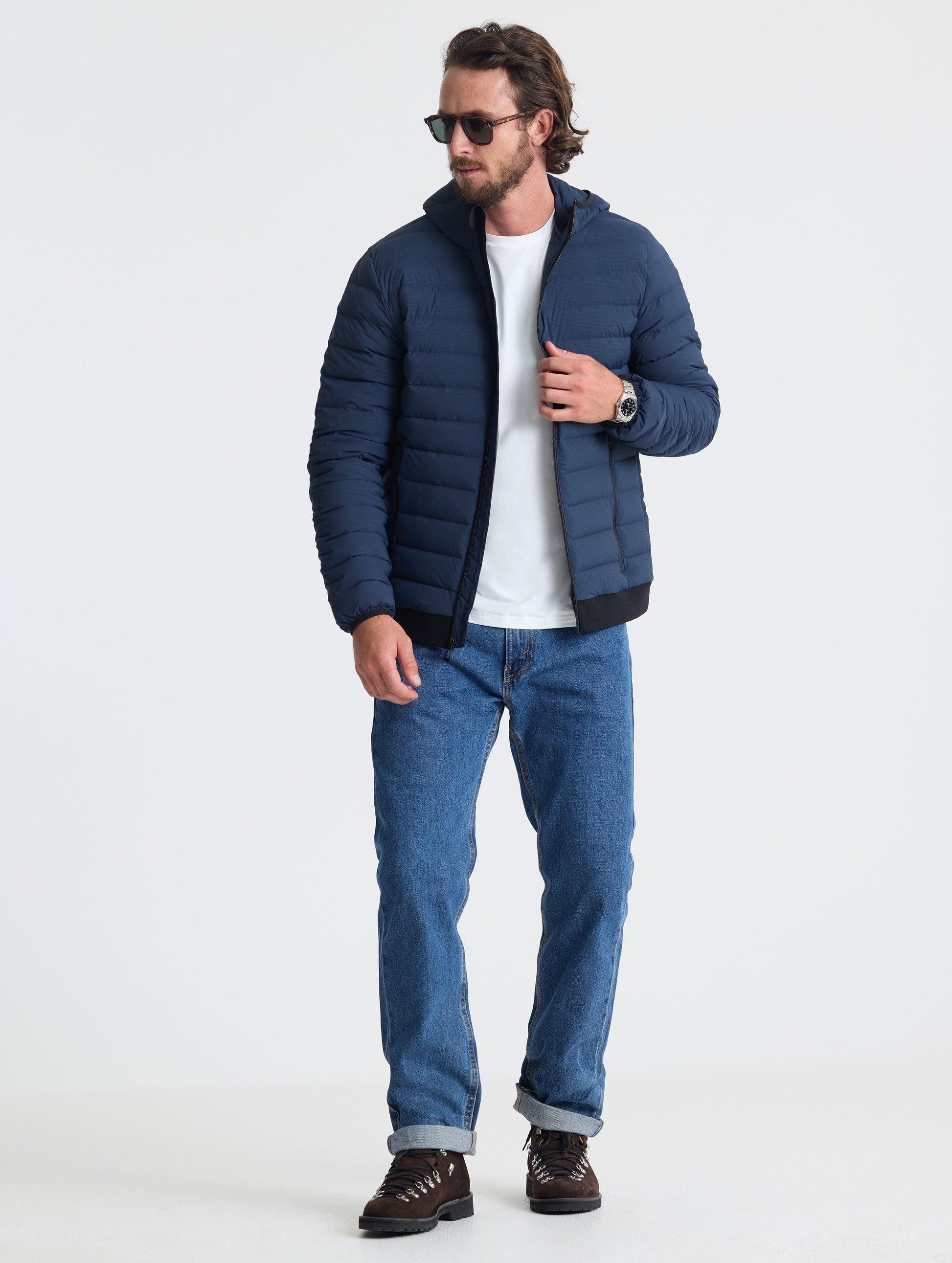 Full body view of man wearing Launch Full-Zip Hooded Jacket in Total Eclipse dark blue from AETHER Apparel.