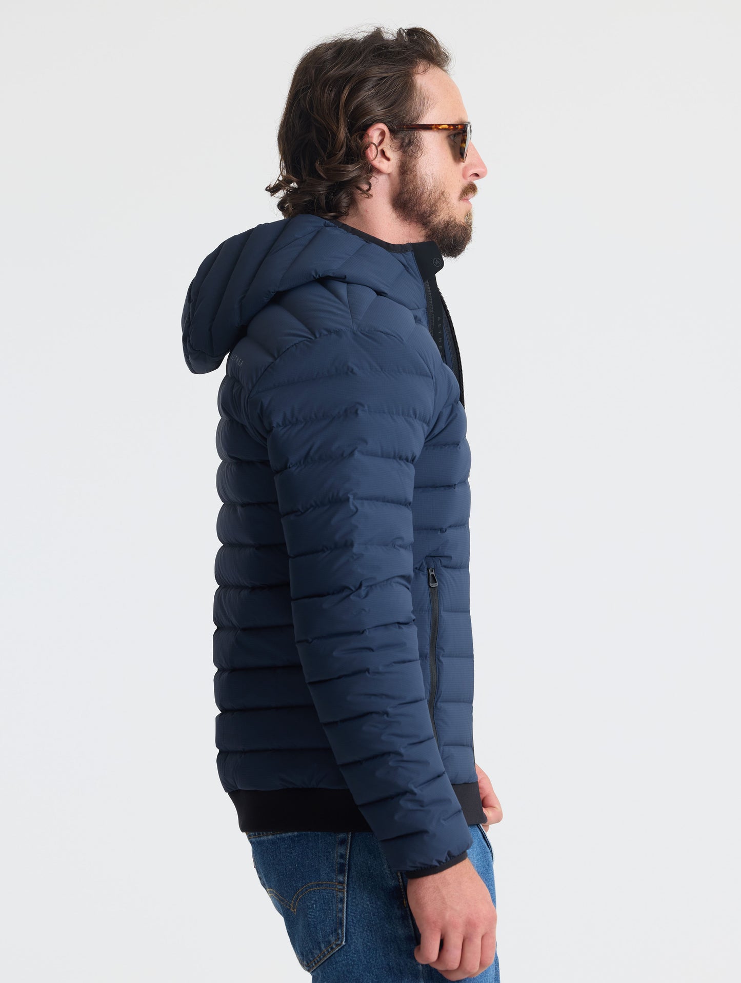 Right profile of man wearing Launch Full-Zip Hooded Jacket in Total Eclipse dark blue from AETHER Apparel.